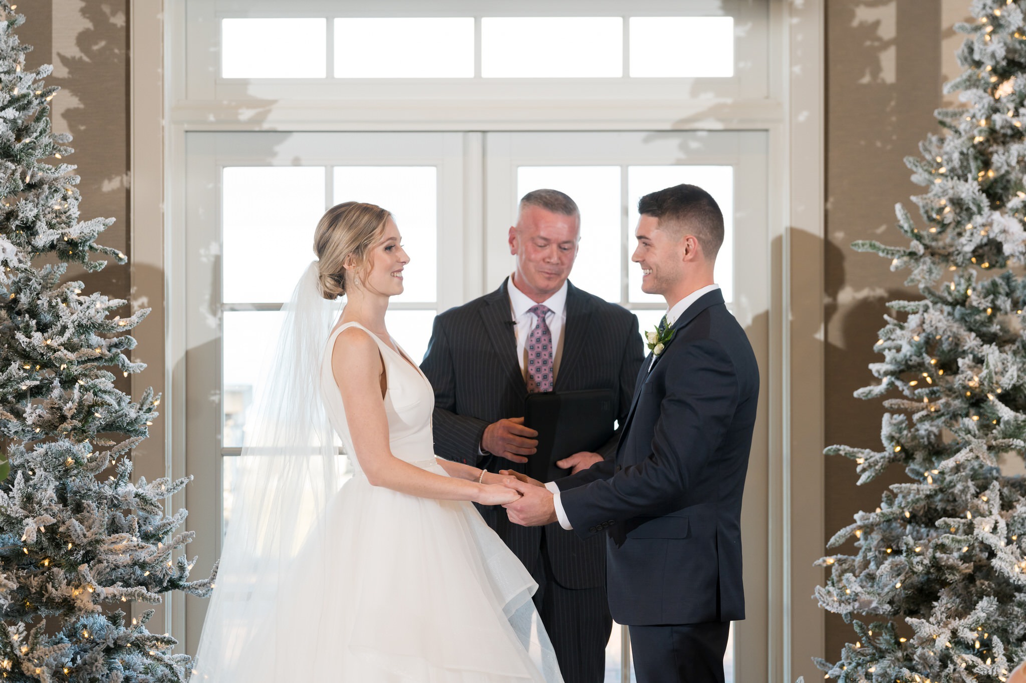 A bride and groom hold hands at their Bay Harbor wedding ceremony in the Sagamore Room. 