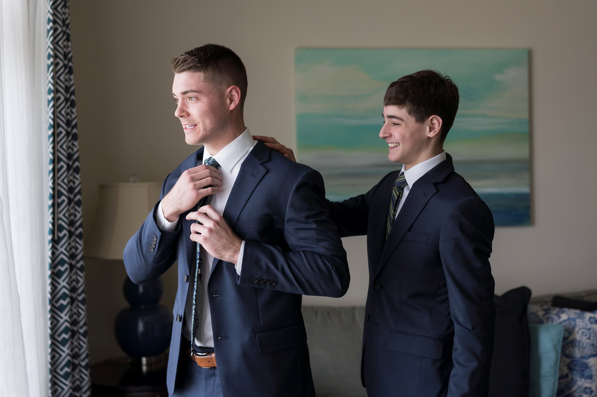 A young brother helps his older brother fix his jacket while getting ready for his Bay Harbor wedding. 