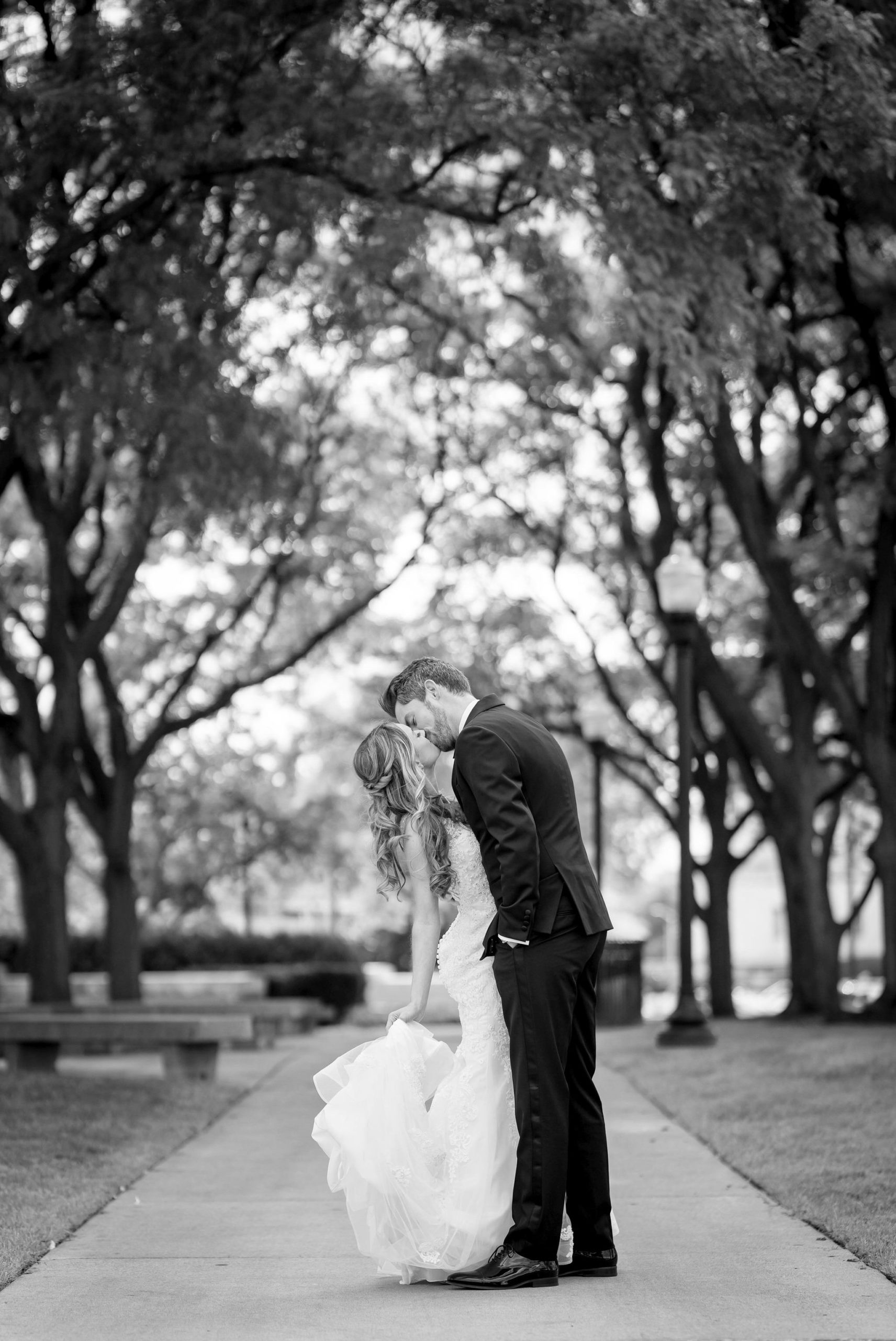 A bride and groom embrace on the sidewalk of the Detroit Institute of Art.