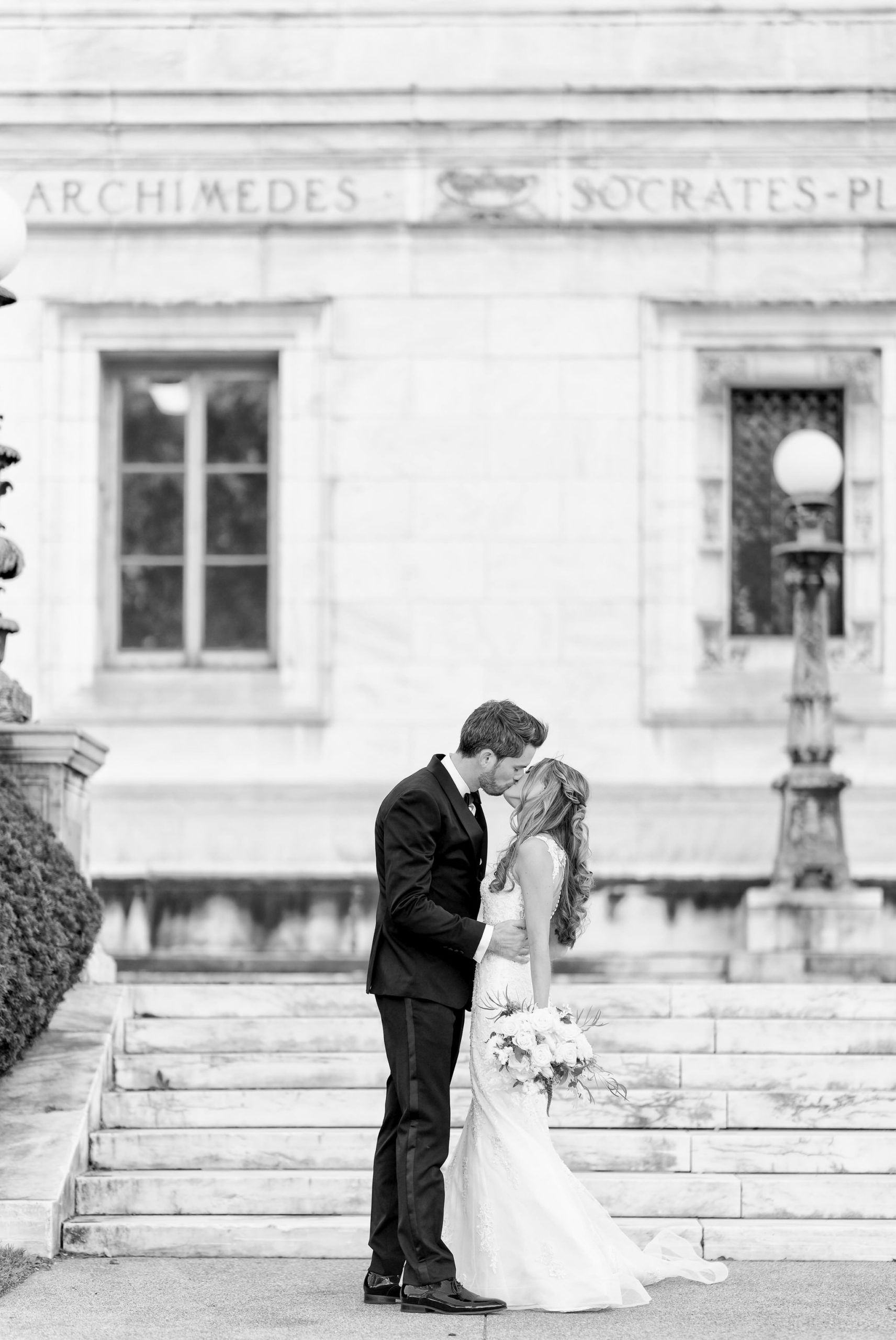 A bride and groom kiss on the stairs of the Detroit Public Library.
