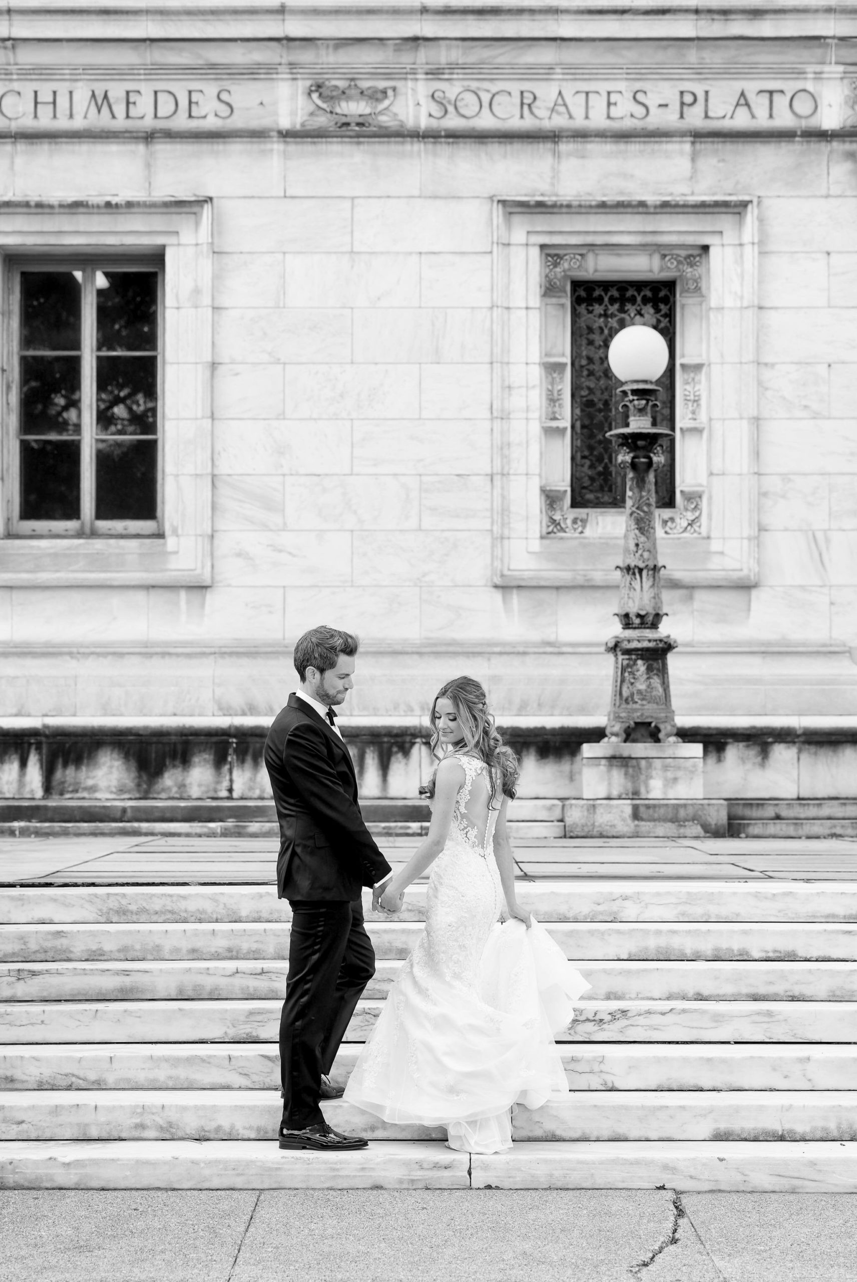 A bride and groom walk up the stairs of the Detroit Public Library.