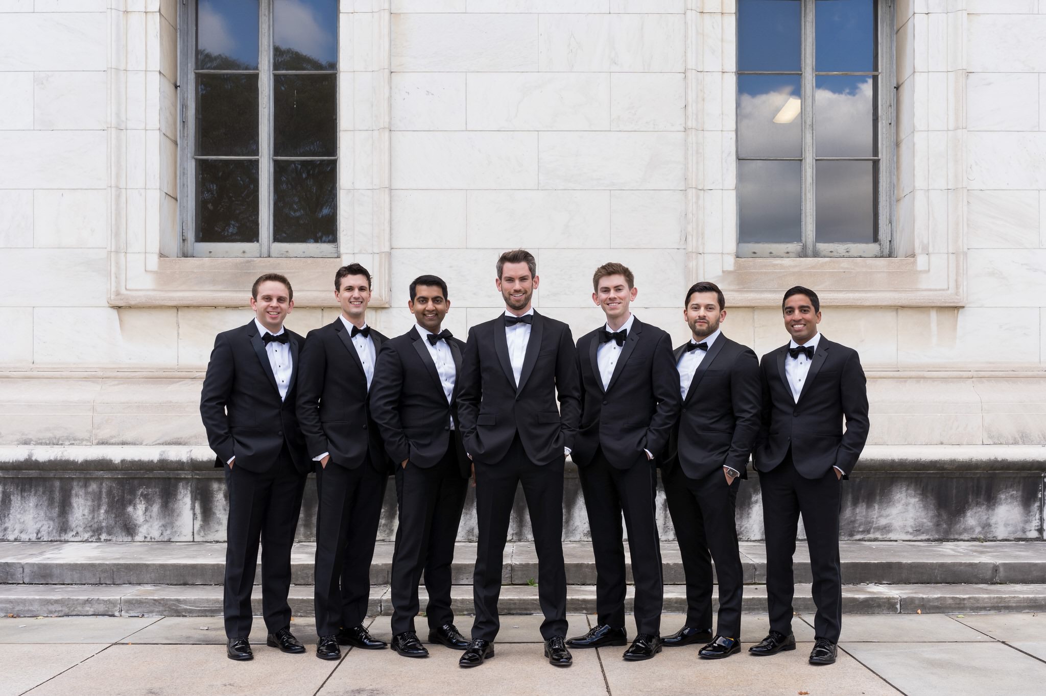 Groomsmen pose with hands in their pockets outside of the  Detroit Public Library.