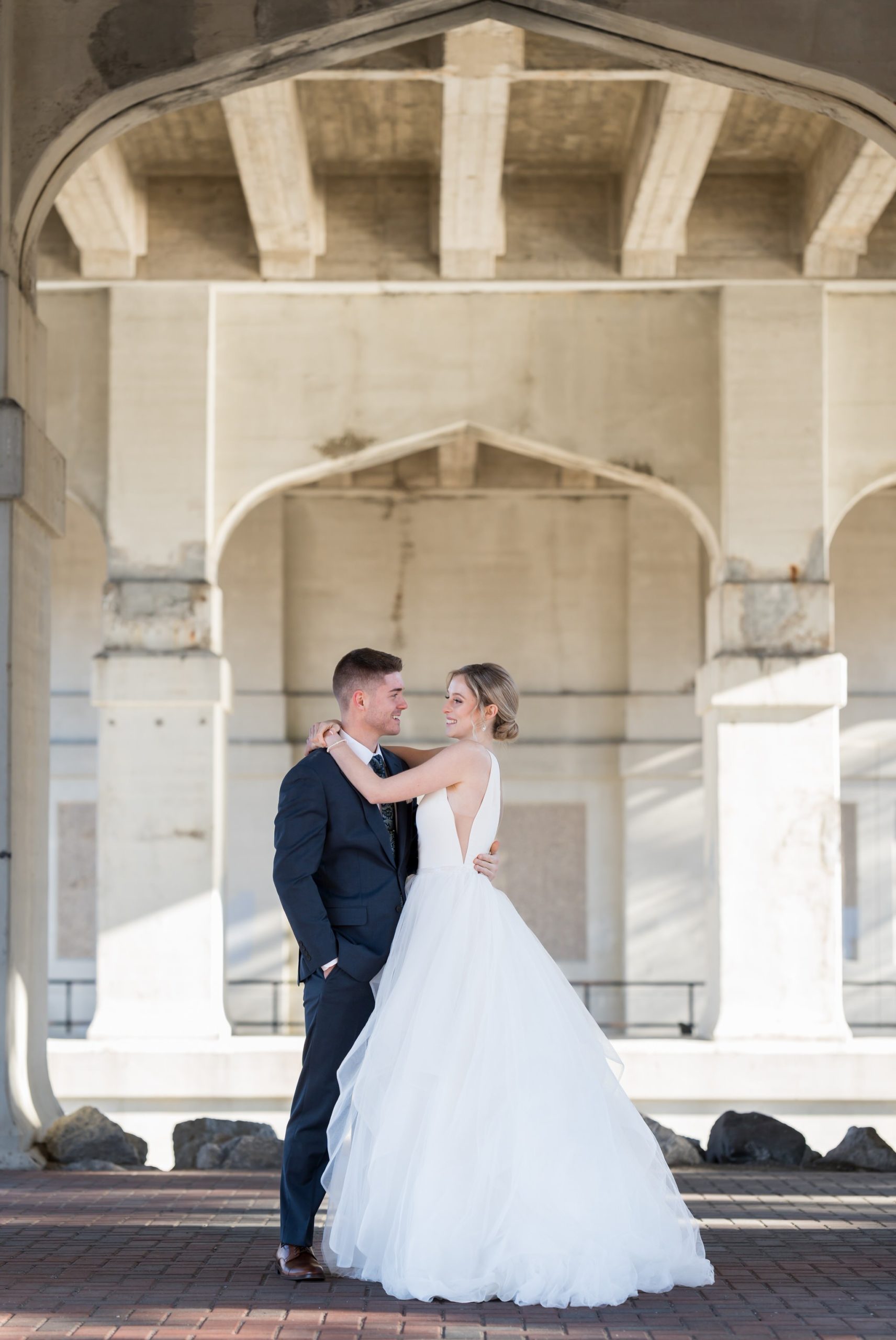 A bride and groom hug under Mitchell Street bridge in downtown Petoskey before their Bay Harbor wedding.
