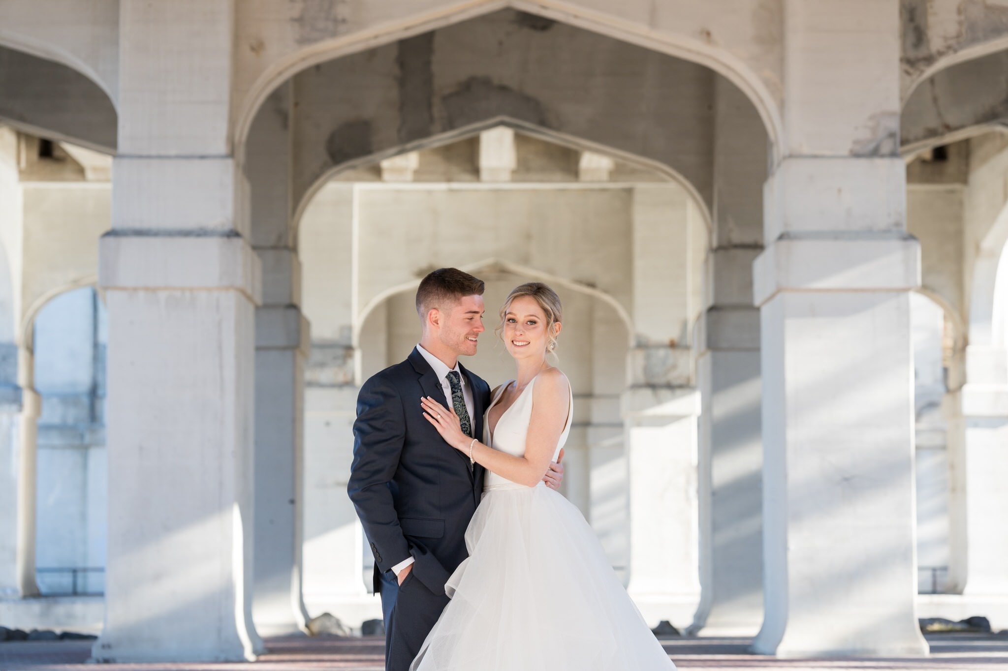 A bride and groom pose under Mitchell Street bridge in downtown Petoskey before their Bay Harbor wedding.