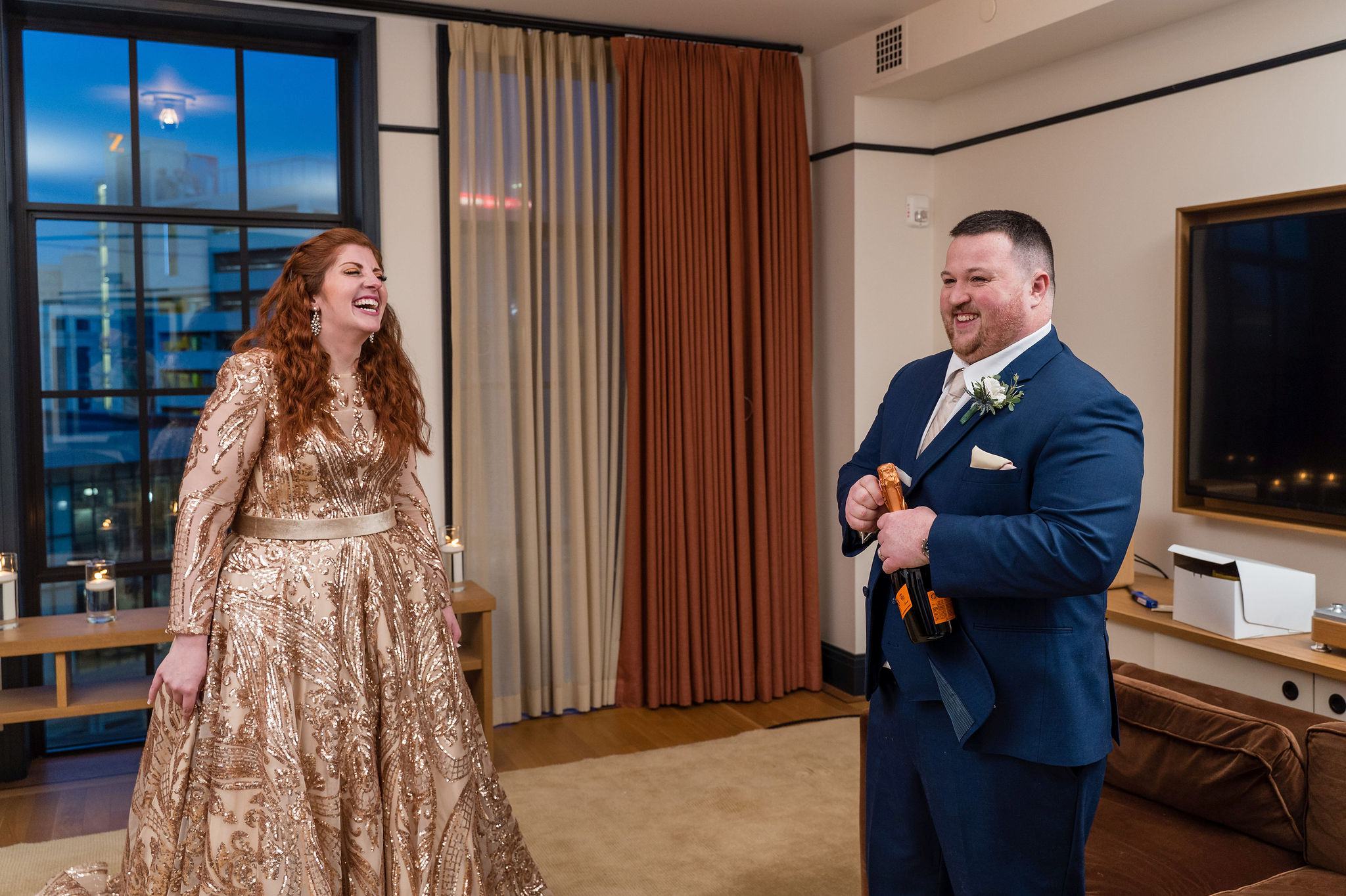 A couple opens a bottle of champagne to celebrate their secret Detroit elopement in a room at the Shinola Hotel. 