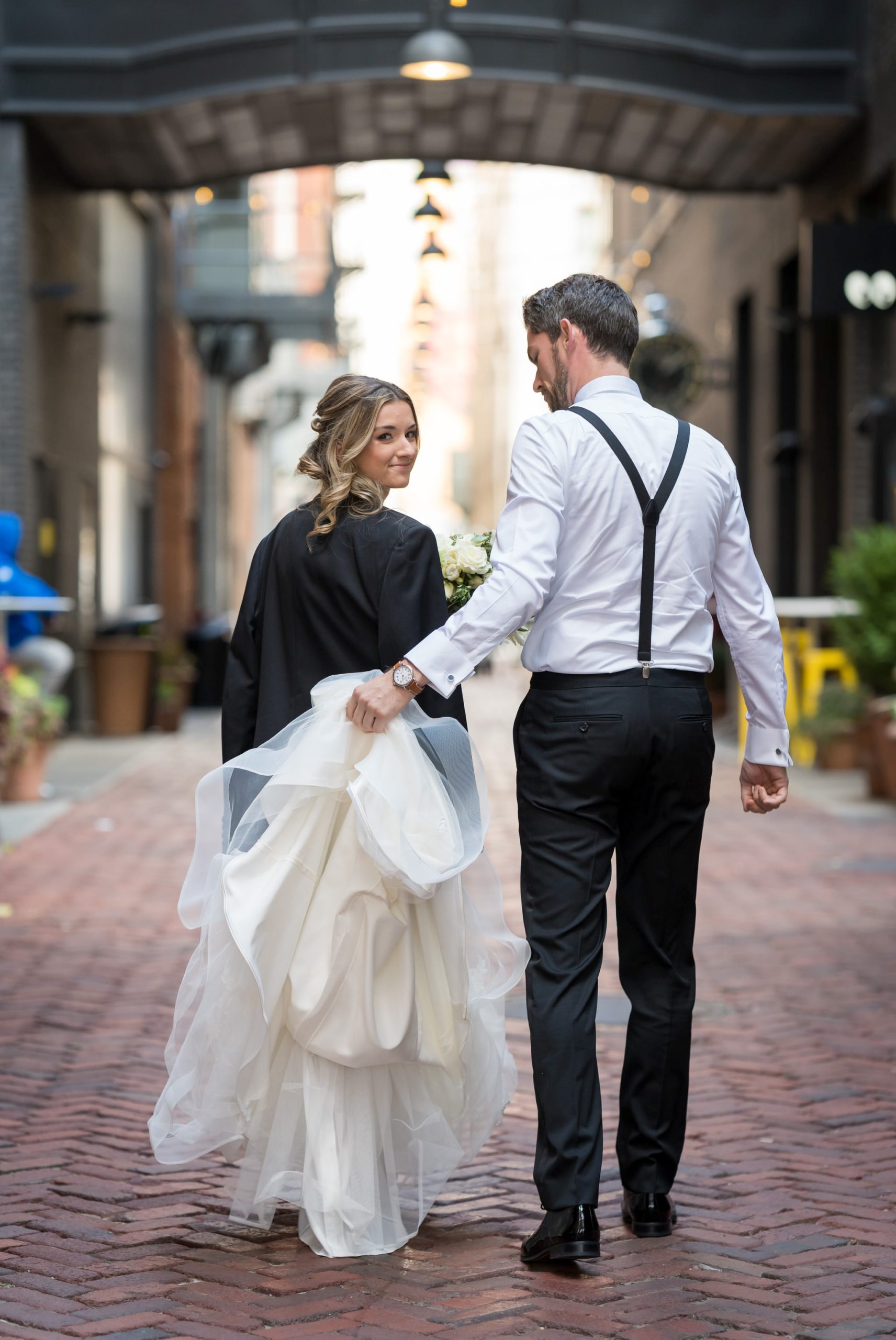 A bride looks over her shoulder while walking down Parker's Alley.  