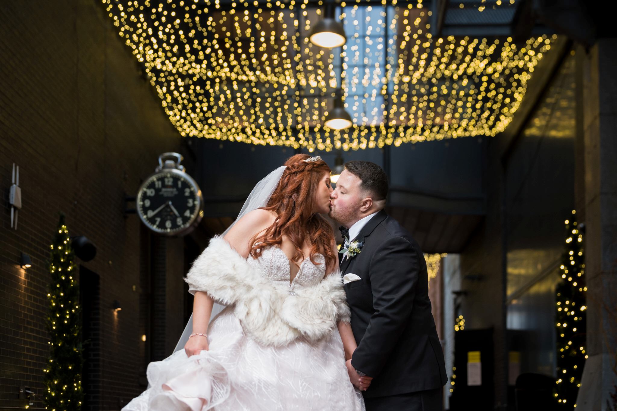 A bride and groom pose with lights in the background in Parker's Alley in Detroit, Michigan. 