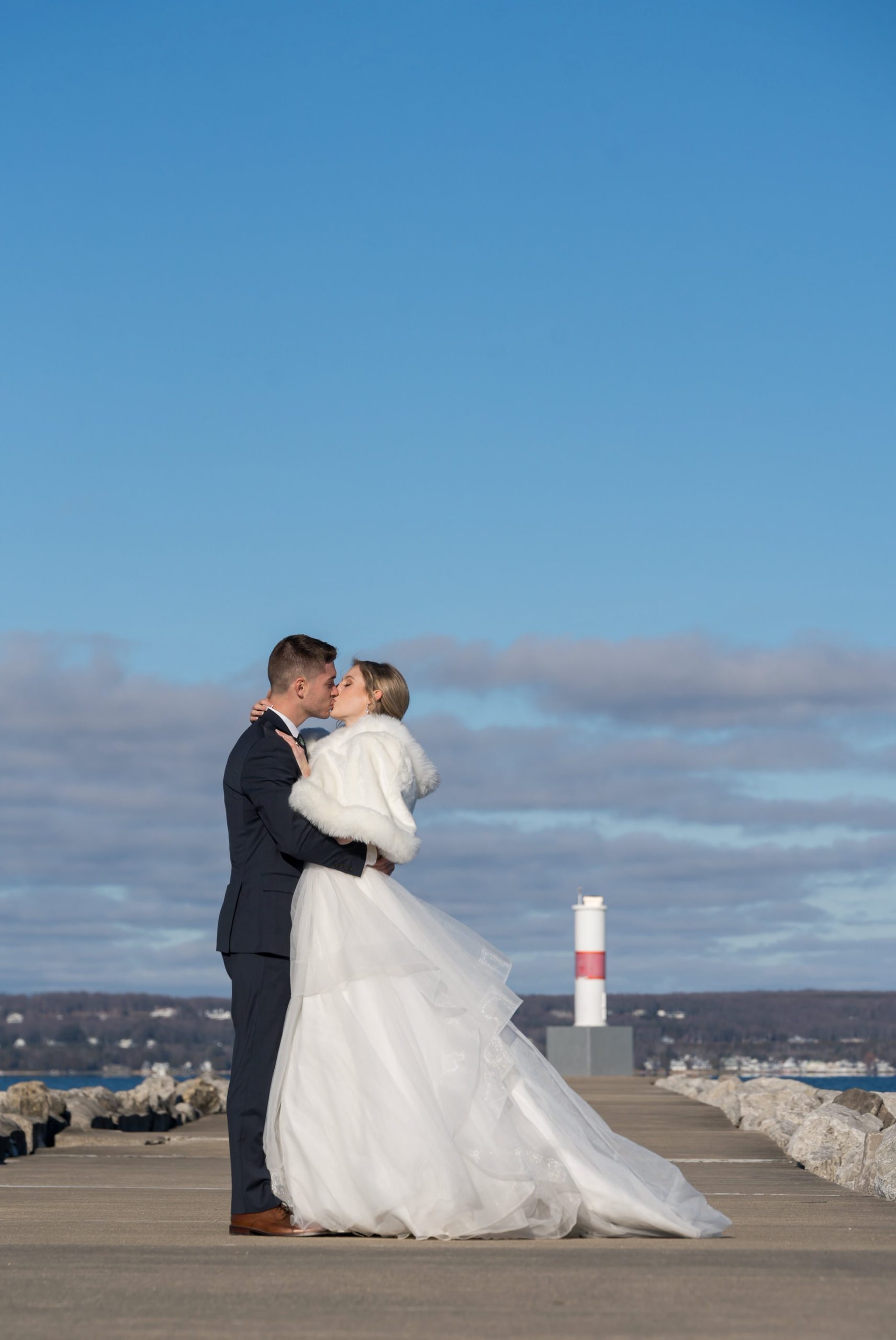 A bride and groom kiss near the Petoskey Pierhead Lighthouse before their Bay Harbor wedding ceremony.  