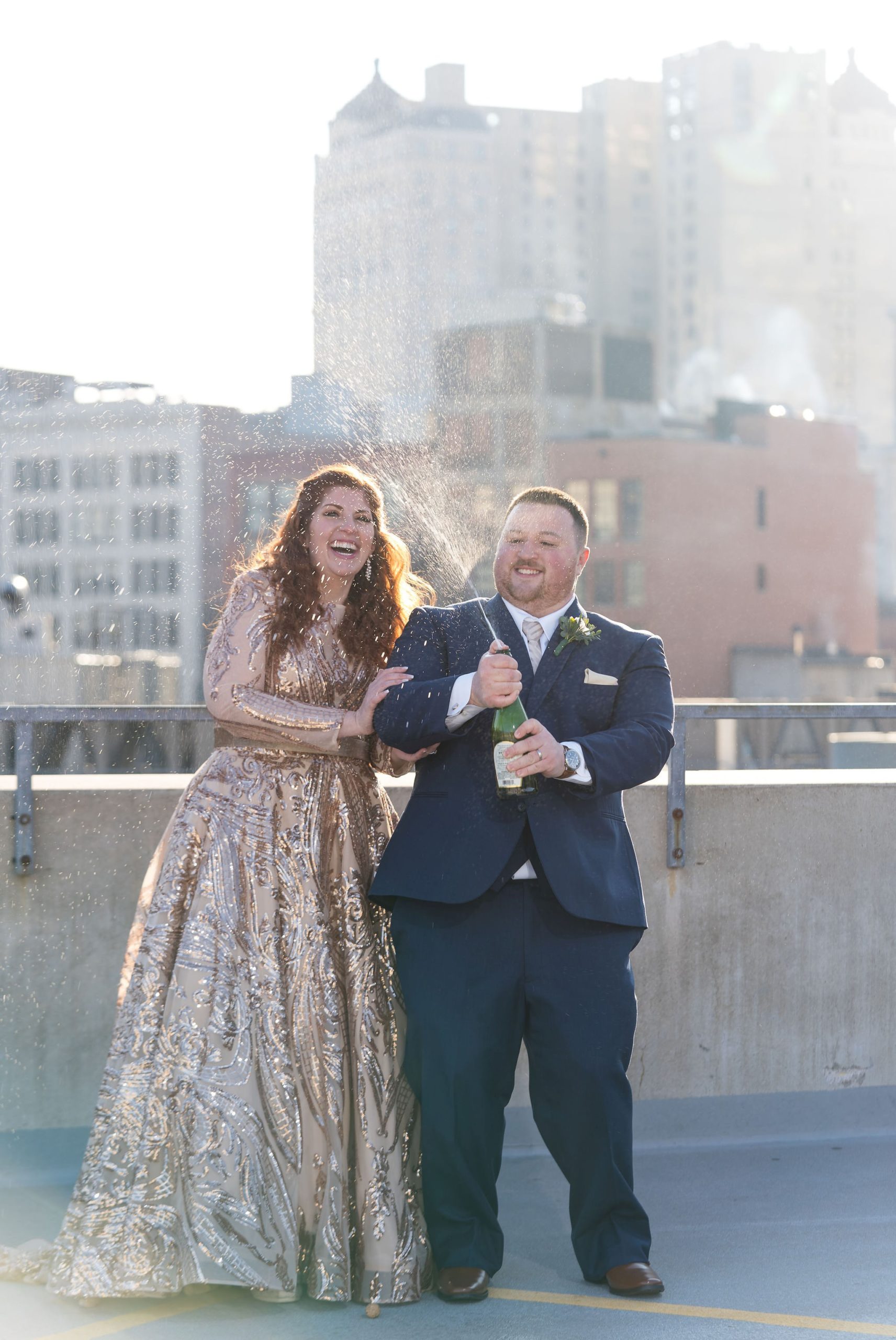 A couple sprays champagne on a rooftop during their Detroit elopement.  