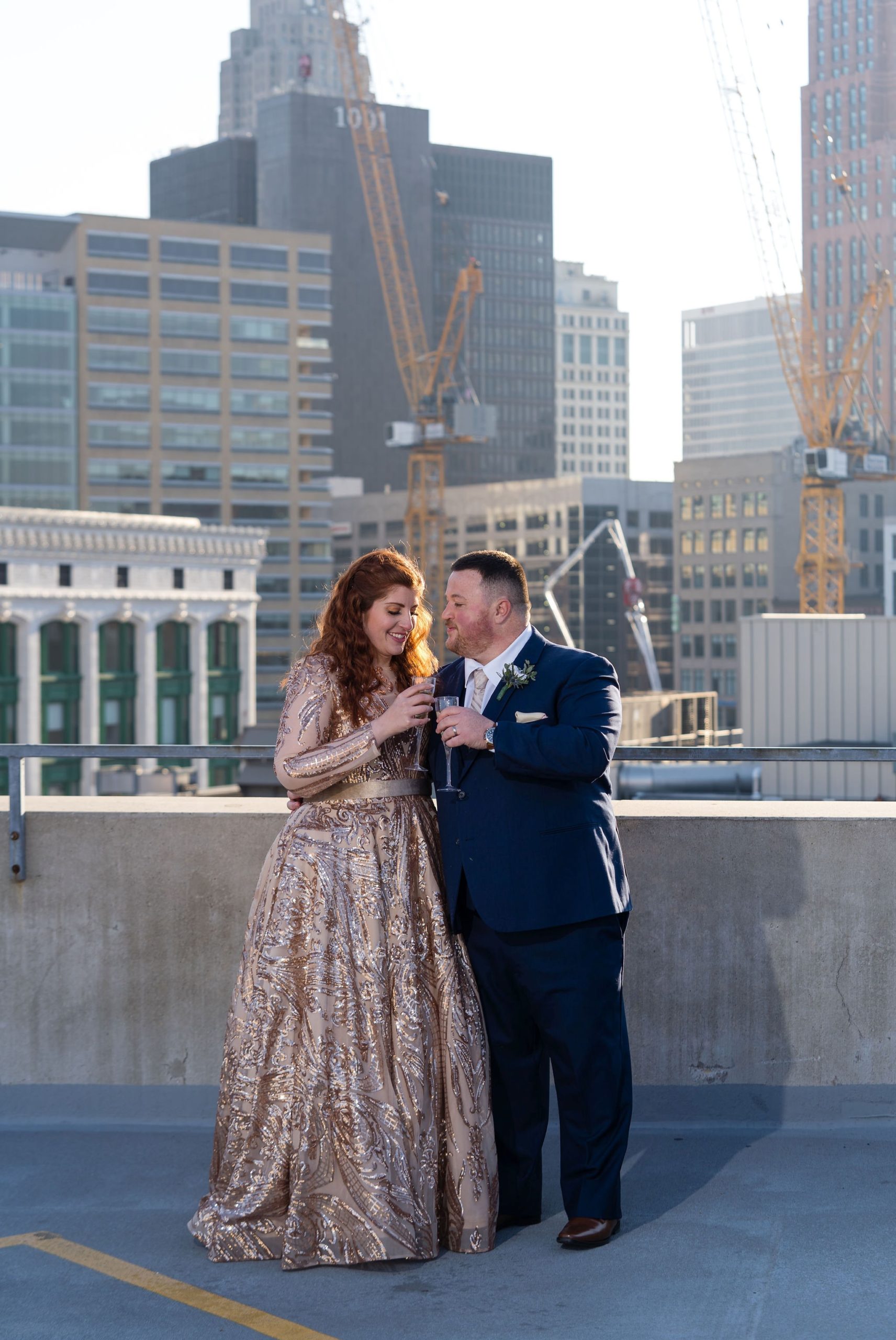 A couple shares glasses of champagne on a rooftop during their Detroit elopement.  