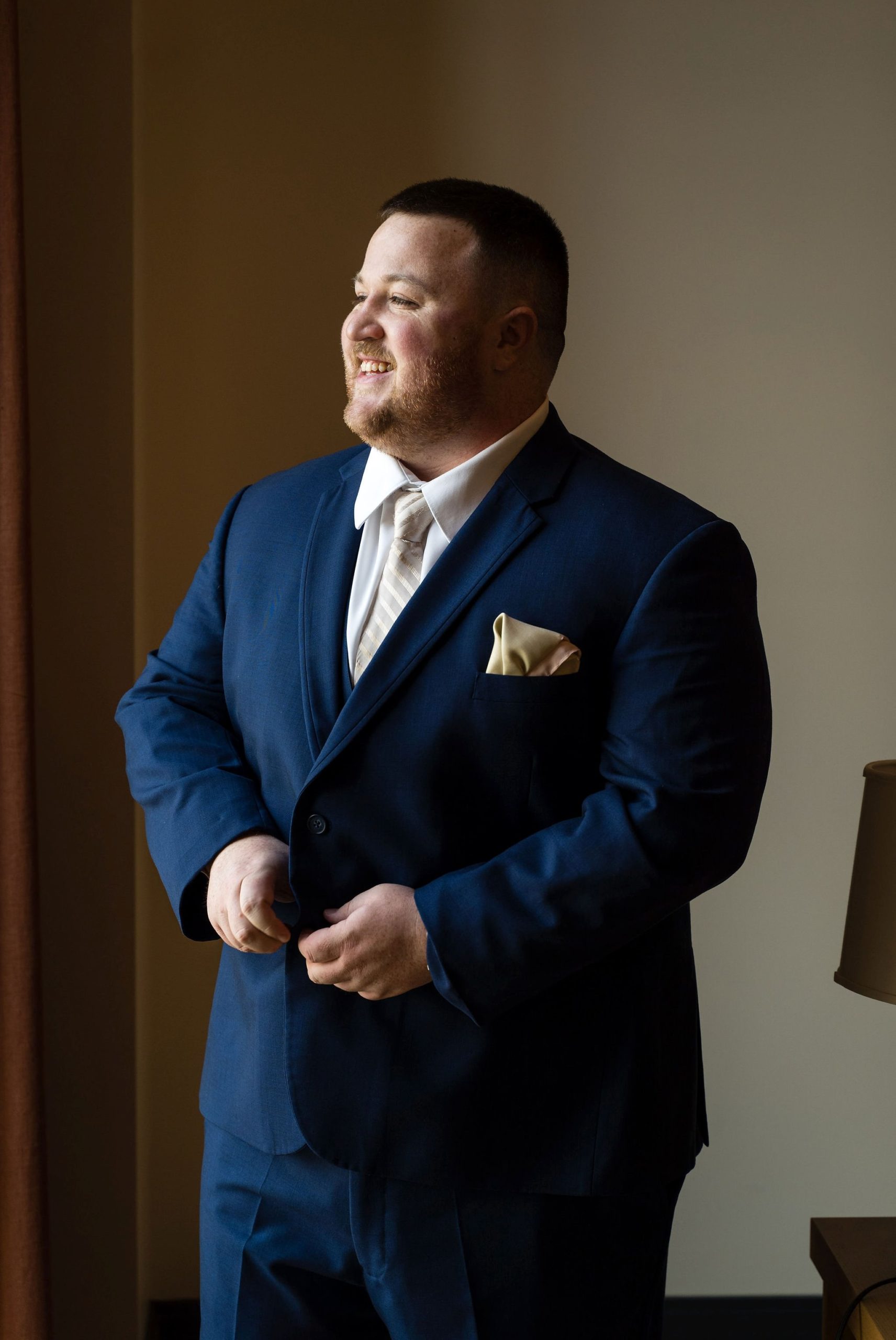 A groom getting ready by a window in the Shinola hotel for his Detroit elopement. 