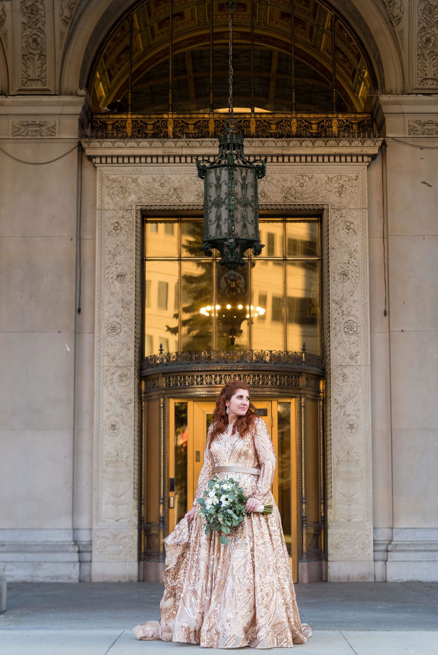 A bride poses in front of a brass door during her Detroit elopement. 