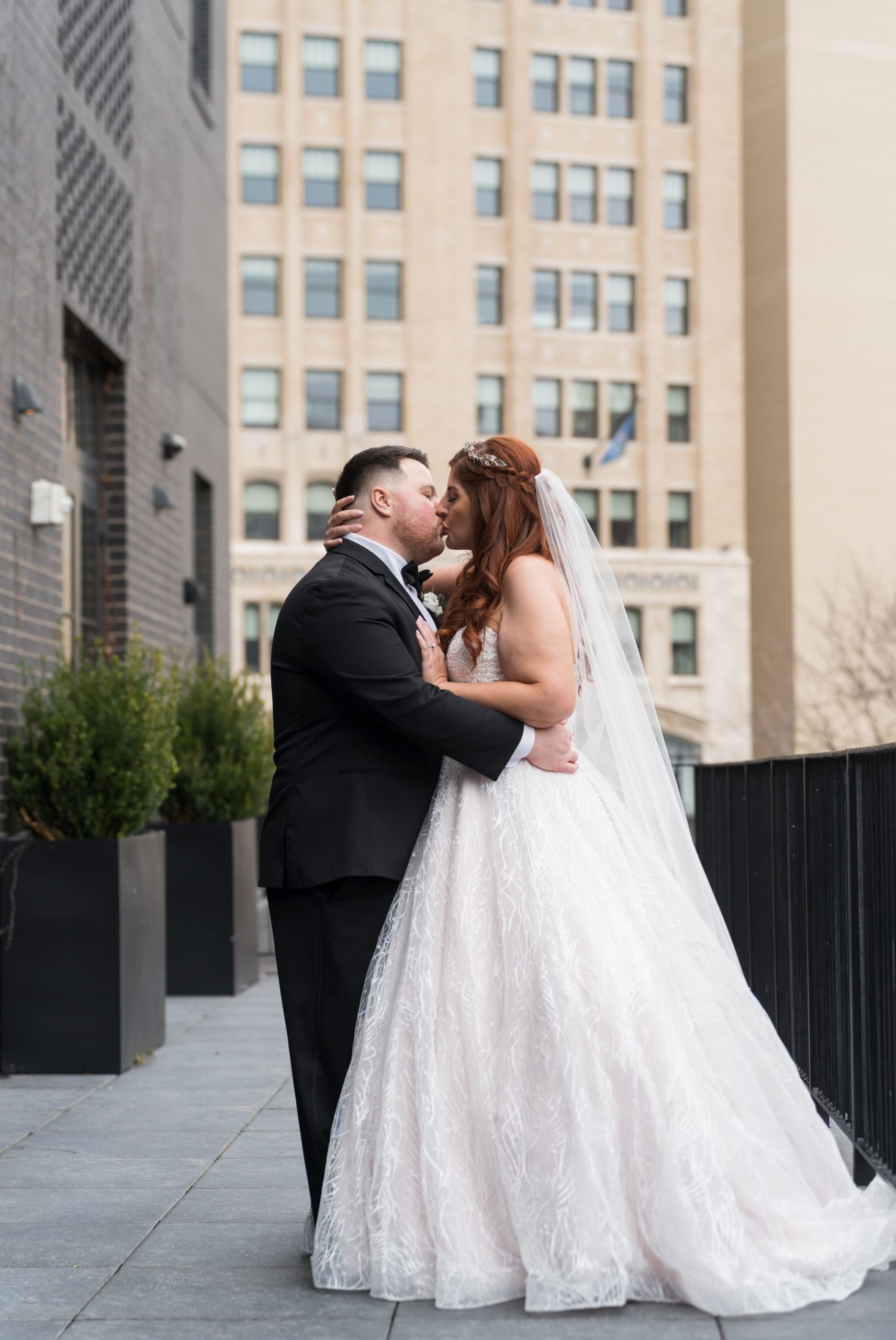 A couple kisses on an outdoor balcony at their Shinola Hotel wedding.   