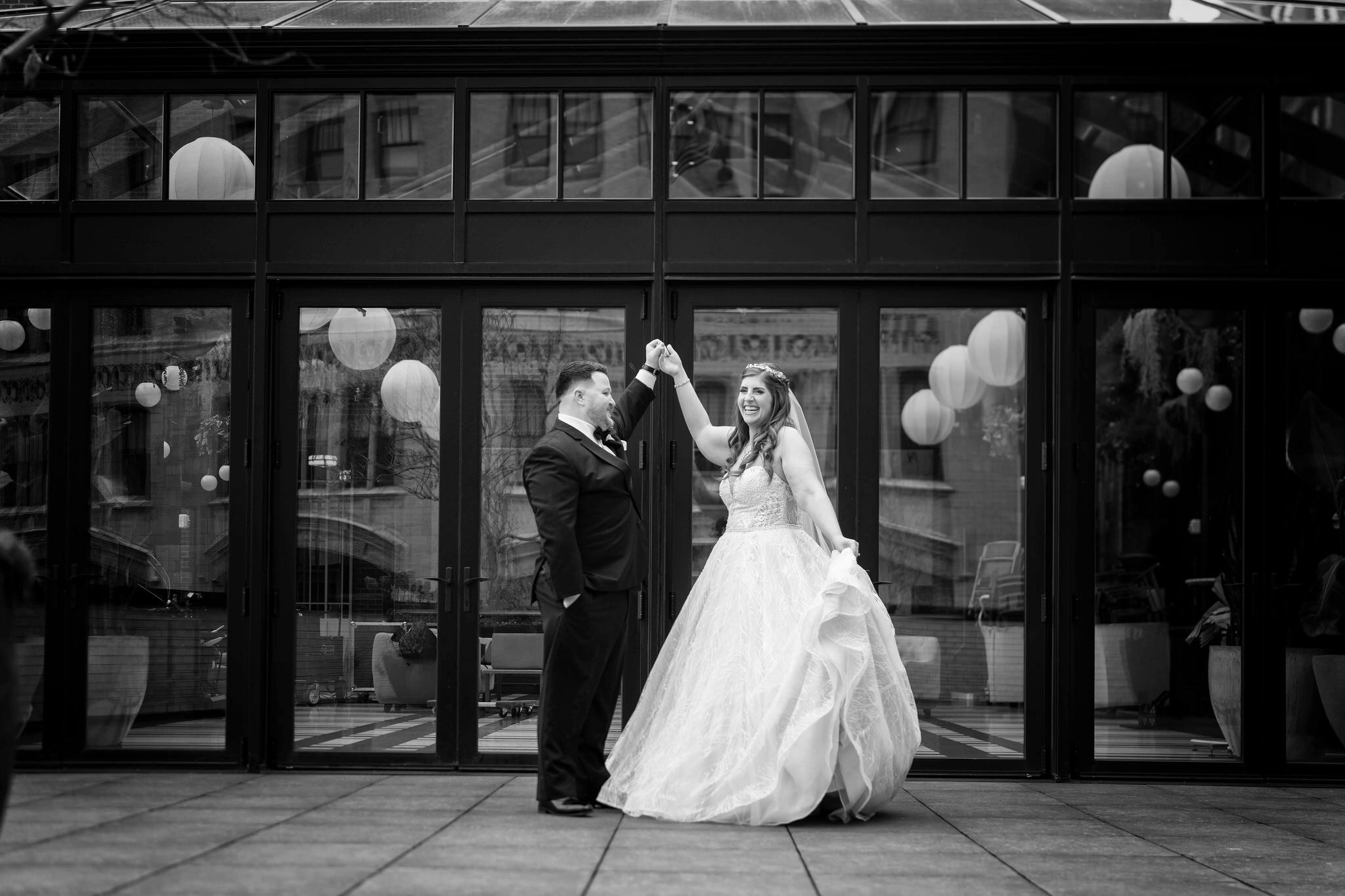 A bride laughs as she twirls on an outdoor balcony at a Shinola Hotel wedding. 