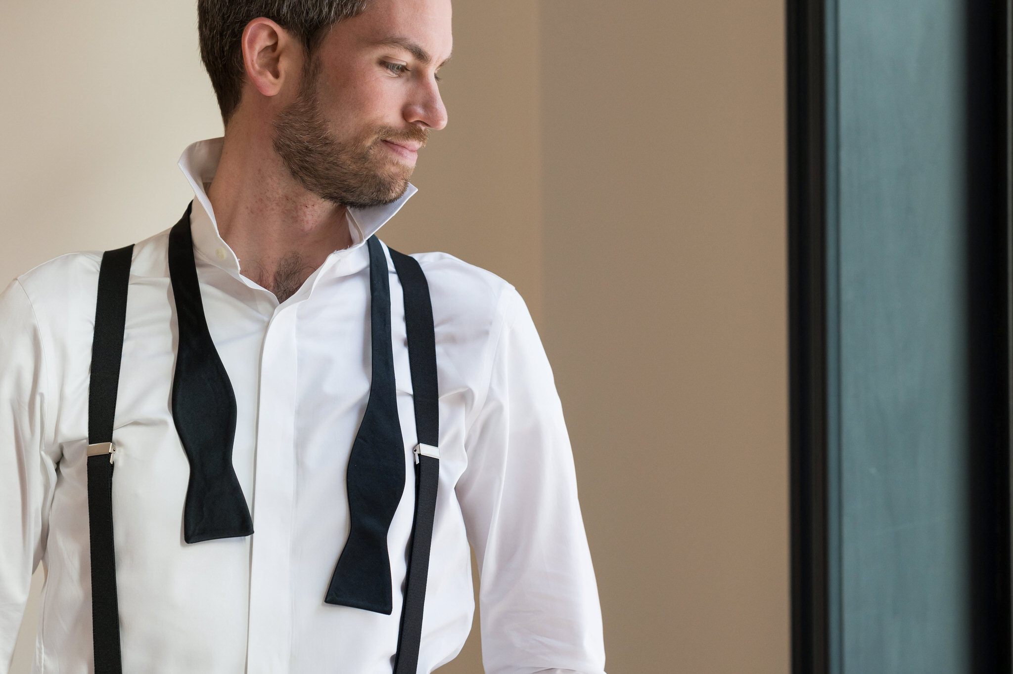 Groom prep with a bowtie hanging around his shoulders at Shinola Hotel. 