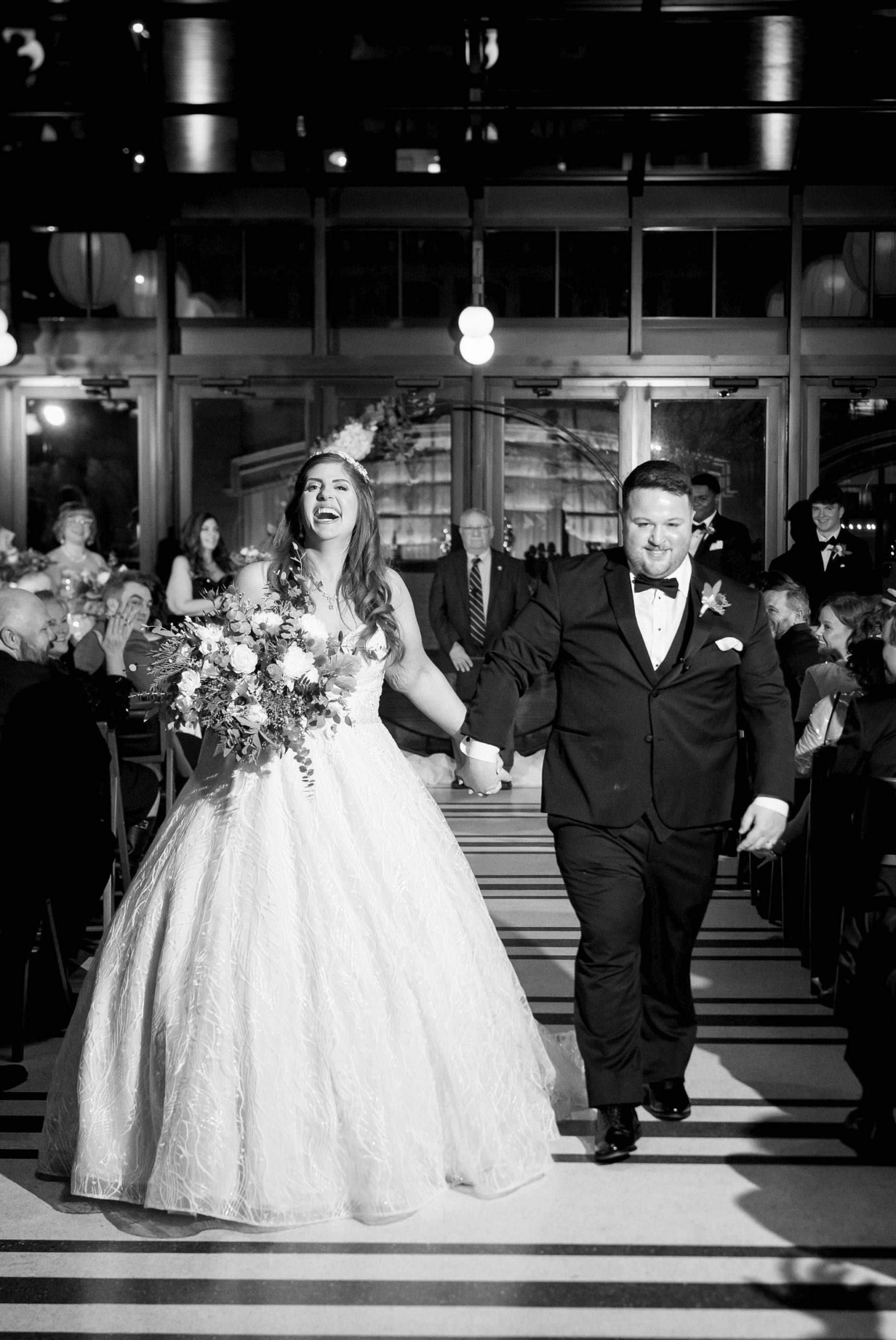 The bride and groom celebrate as they walk down the aisle of their Shinola Hotel wedding. 