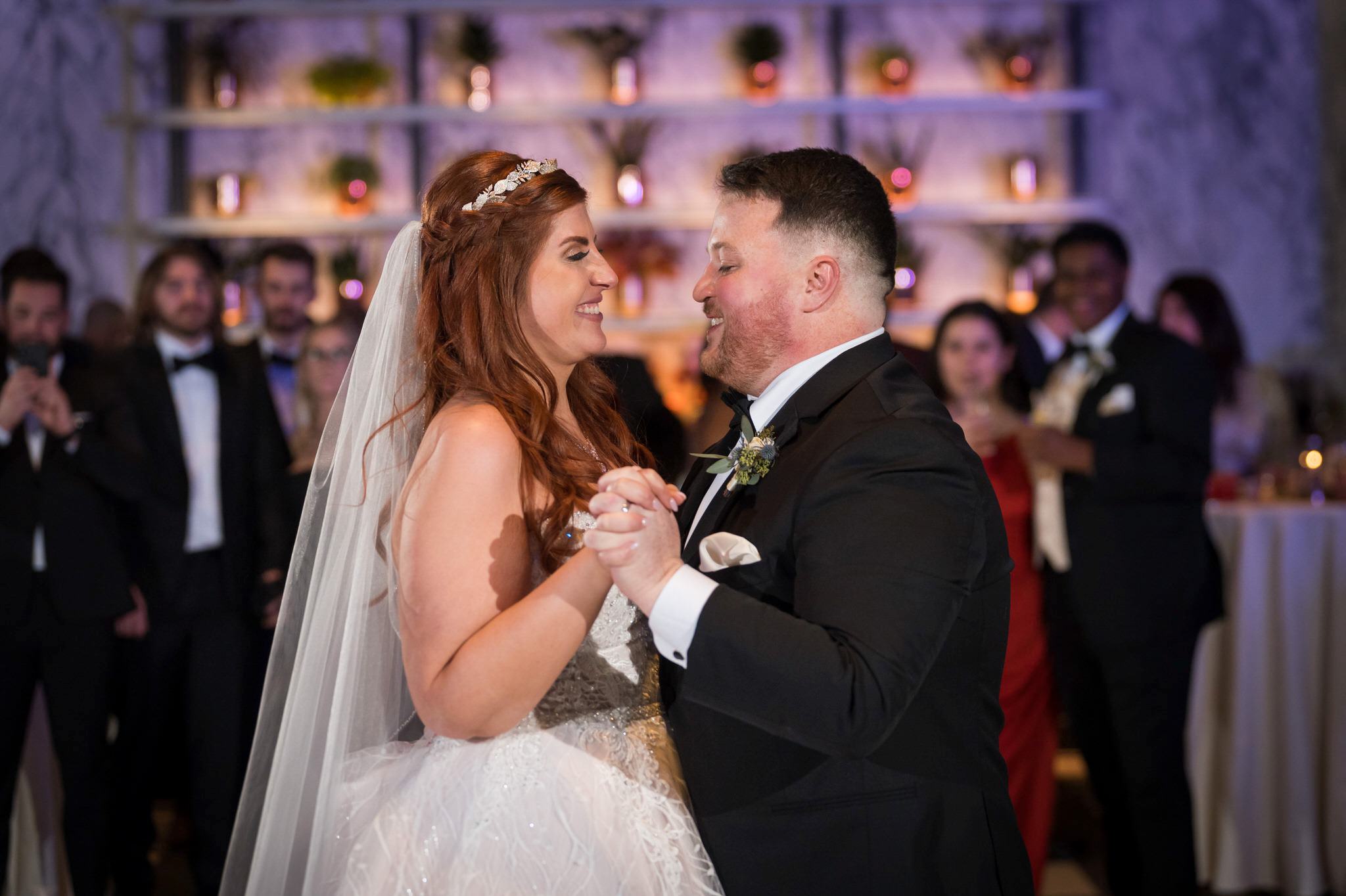 Accented with purple uplighting, a bride and groom share a first dance at their Shinola Hotel wedding reception.