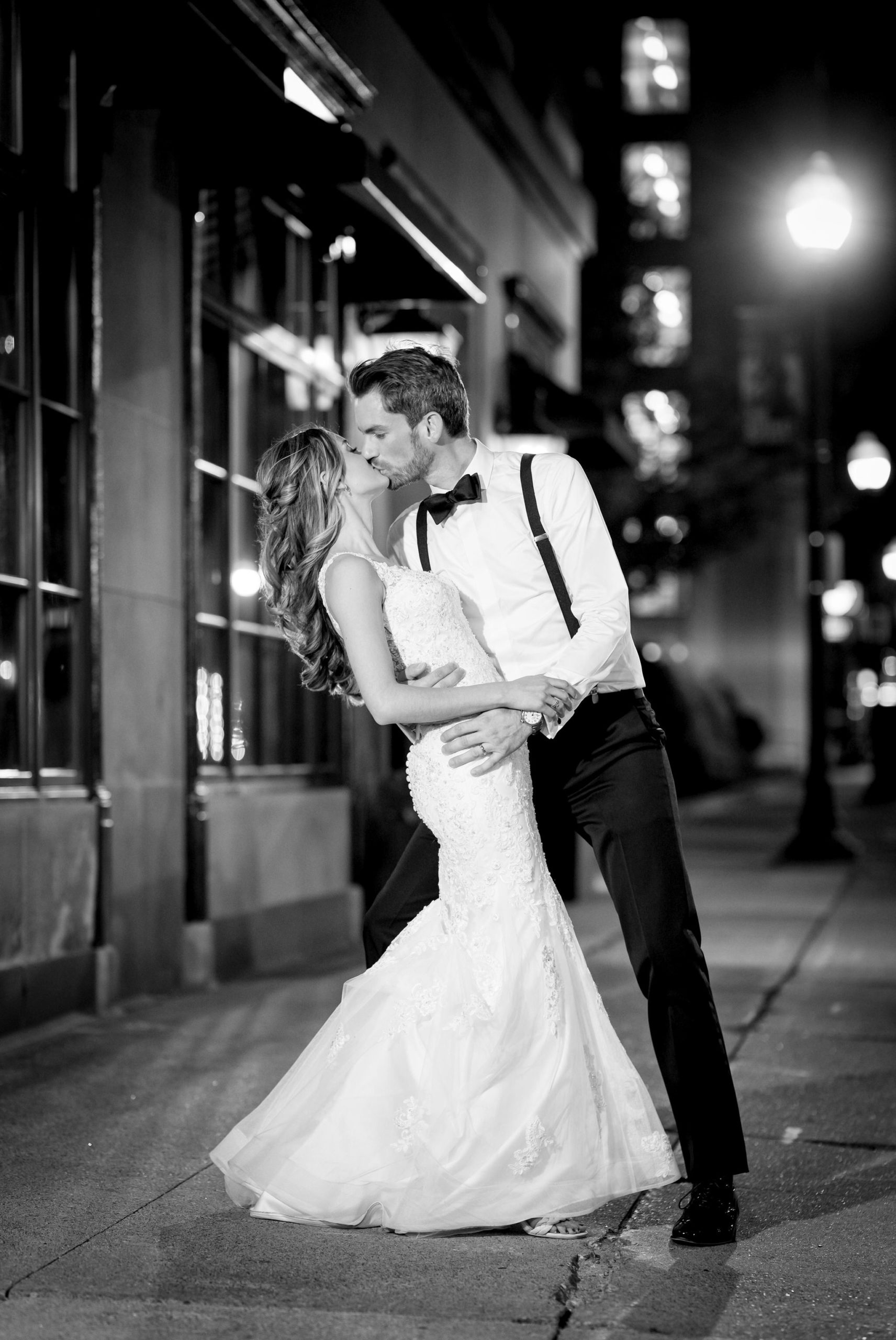 Bride and groom kiss under street lights at their wedding at Detroit's Colony Club.
