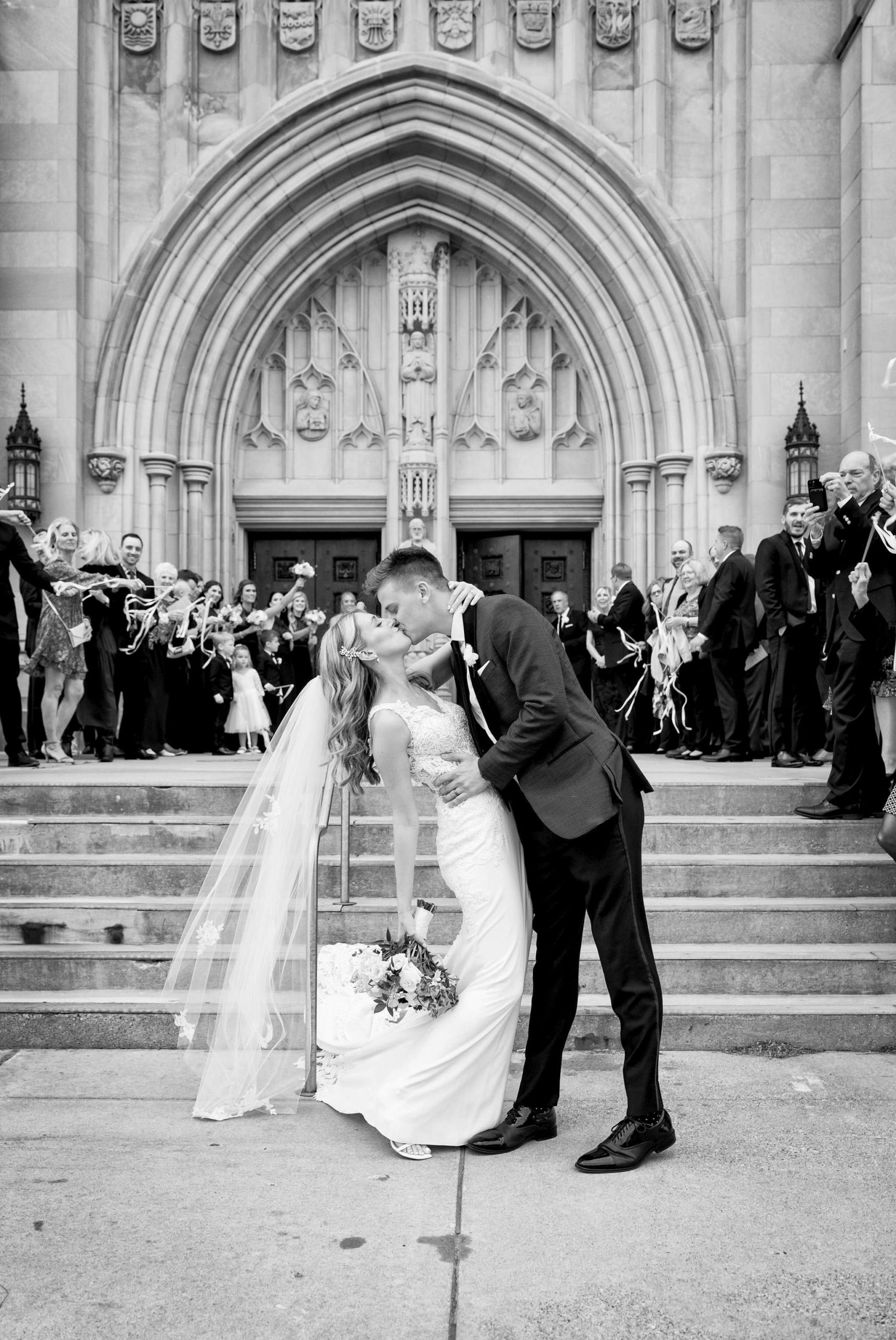 A bride and groom kiss during their grand exit outside of the Cathedral of the Most Blessed Sacrament.  