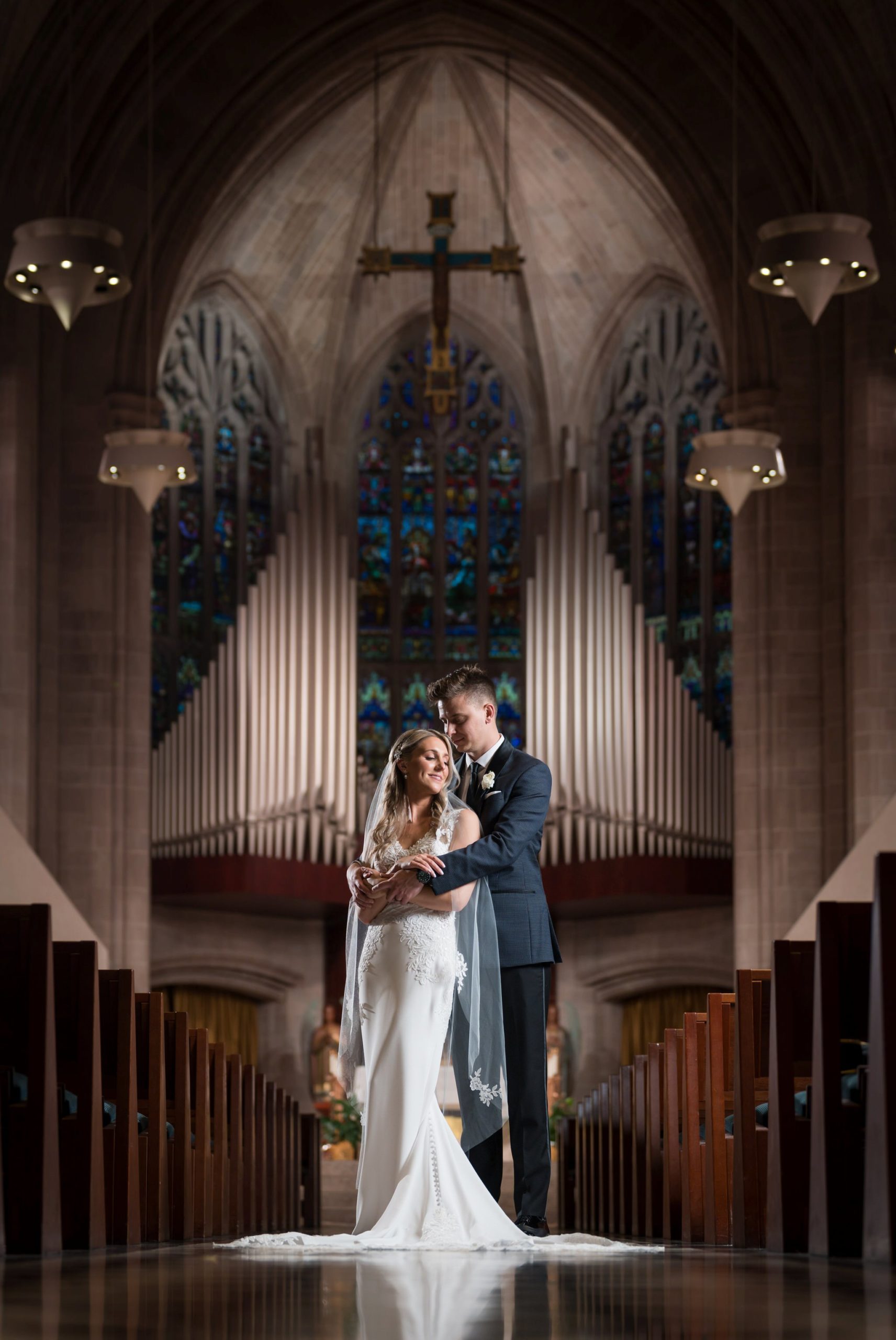 A bride and groom pose in the aisle of the Cathedral of the Most Blessed Sacrament.  