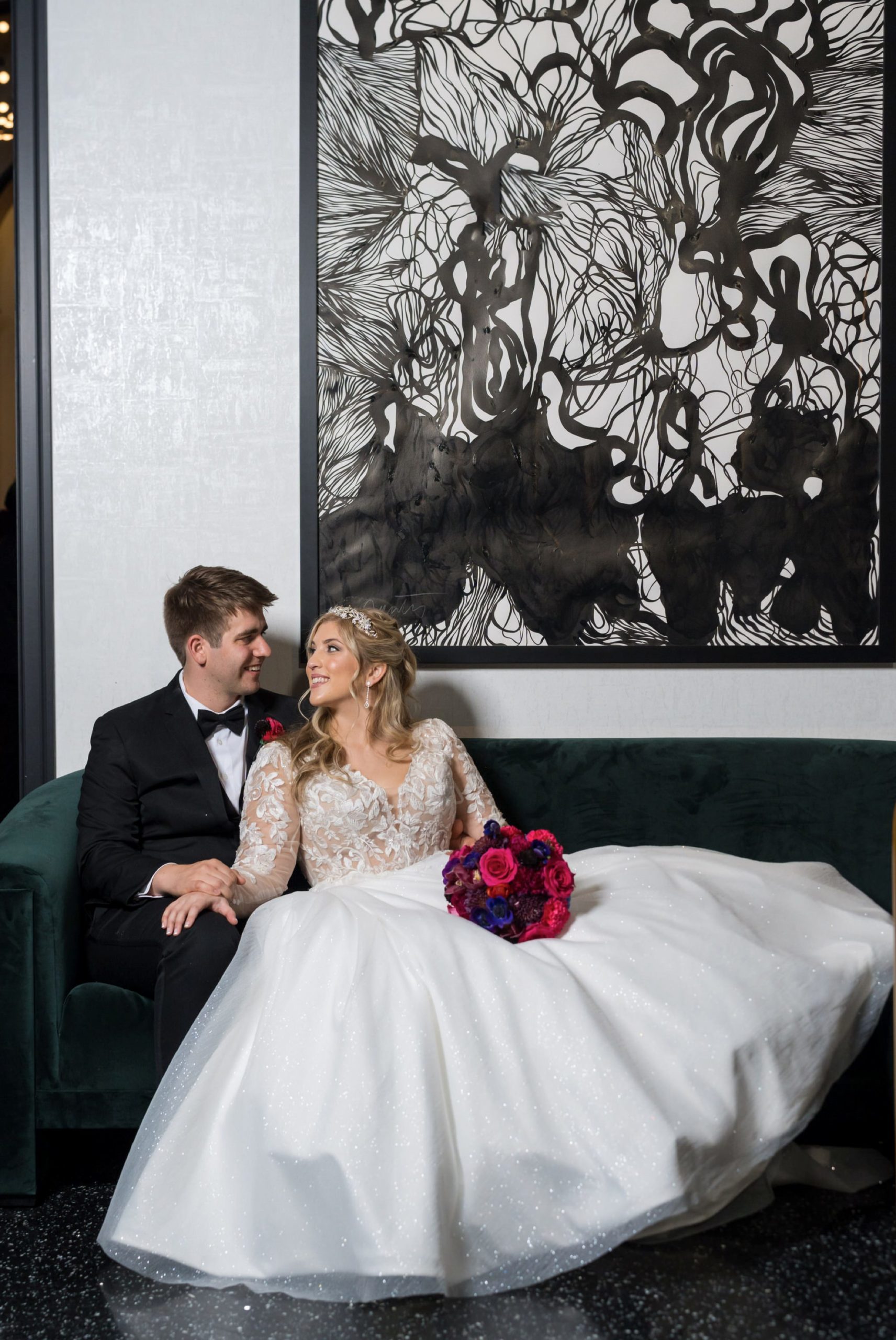 A bride and groom pose, seating in the lobby during their Daxton Hotel wedding.  