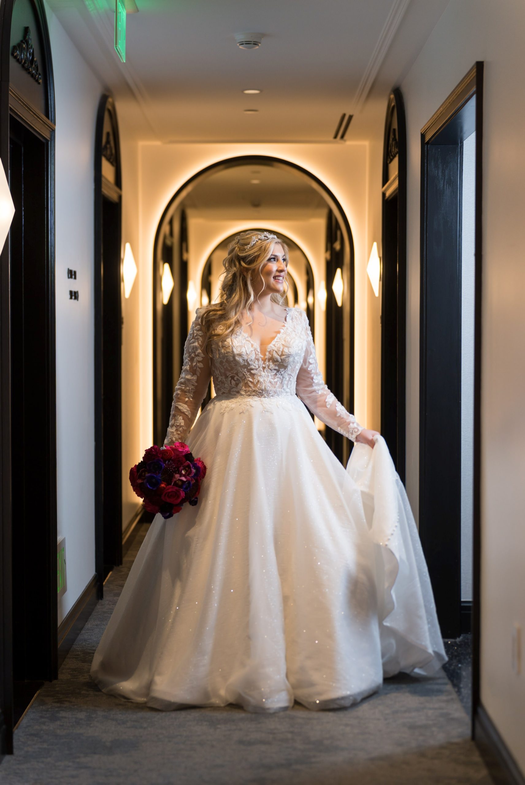 A bride poses in the arched hallway of their Daxton Hotel wedding.  
