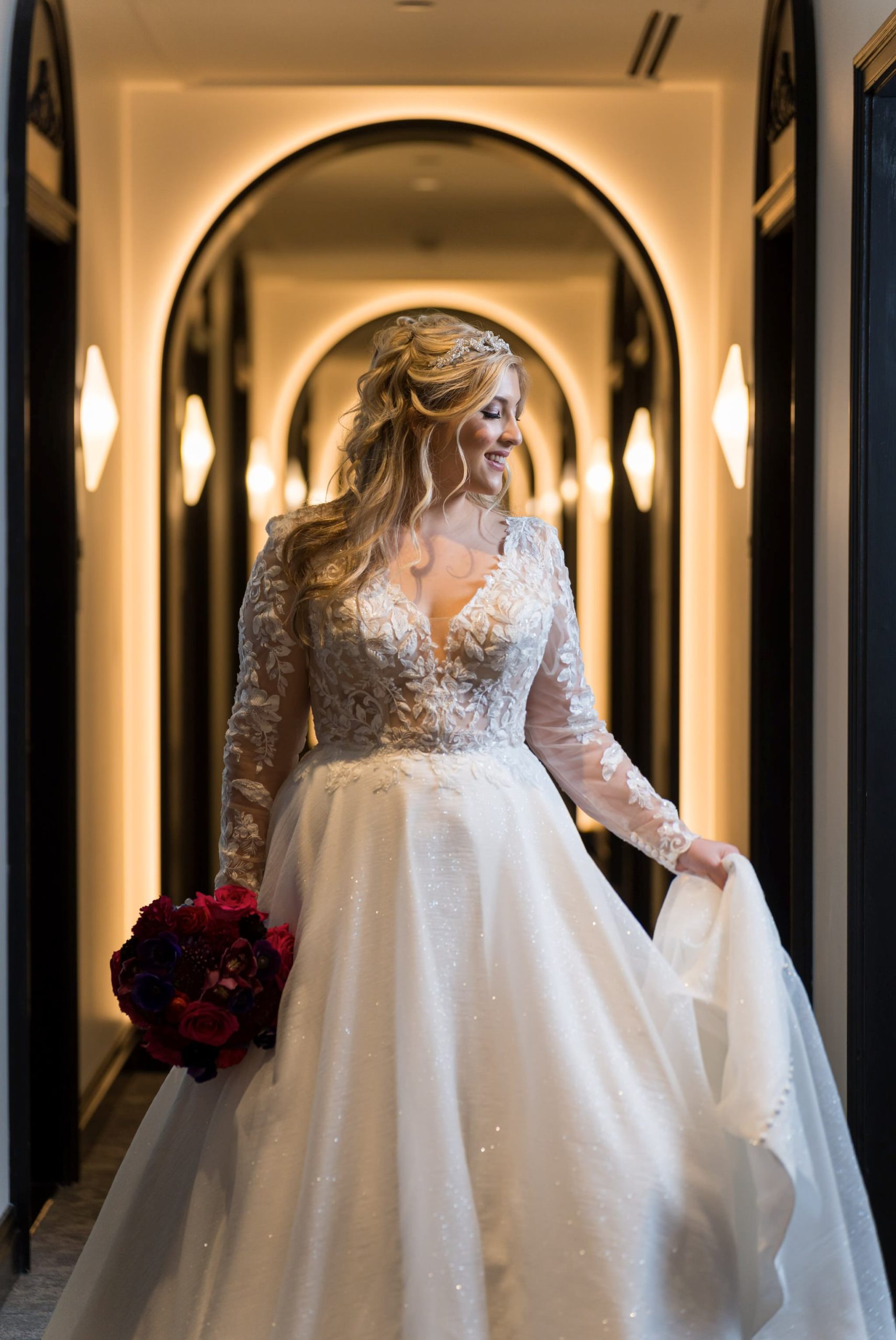 A bride poses in the arched hallway of their Daxton Hotel wedding.  