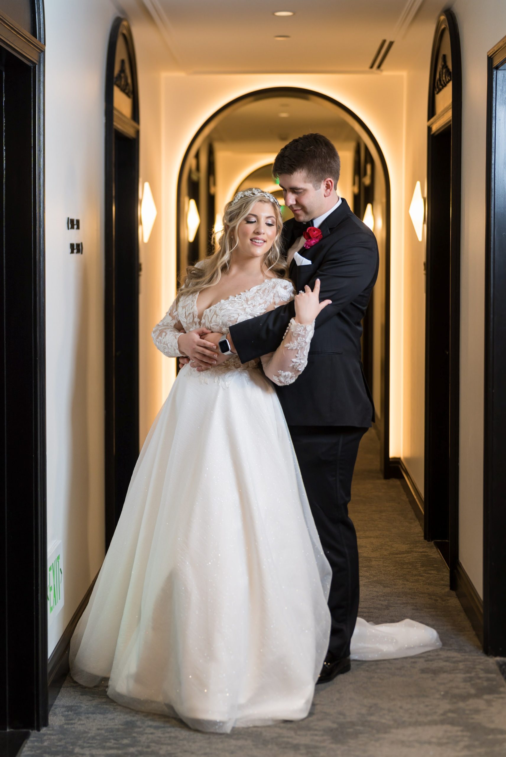 A bride and groom pose in the arched hallway of their Daxton Hotel wedding.  