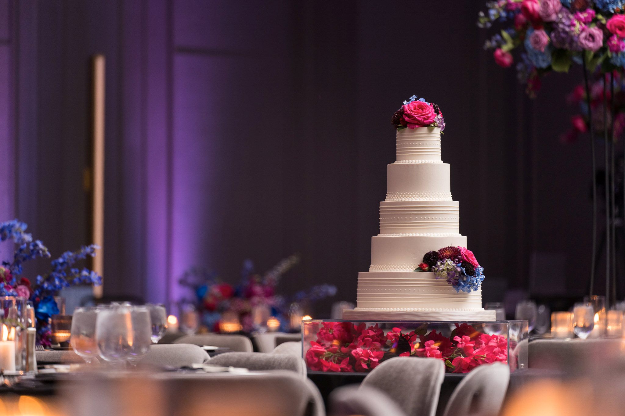 A white wedding cake by Bella e Dolce sits in a elegant ballroom at the Daxton Hotel. 