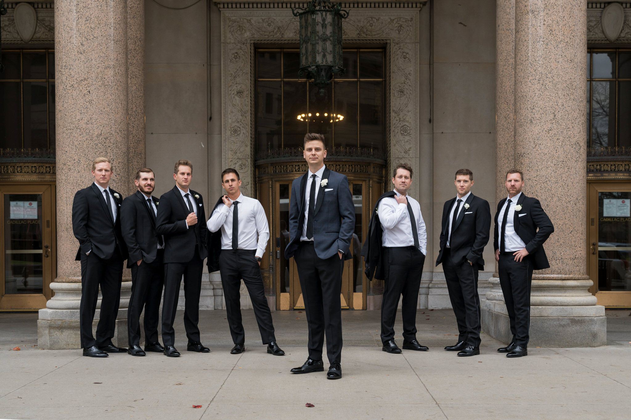 Groomsmen casually pose in front of the Cadillac Place apartments in Detroit, MI.   