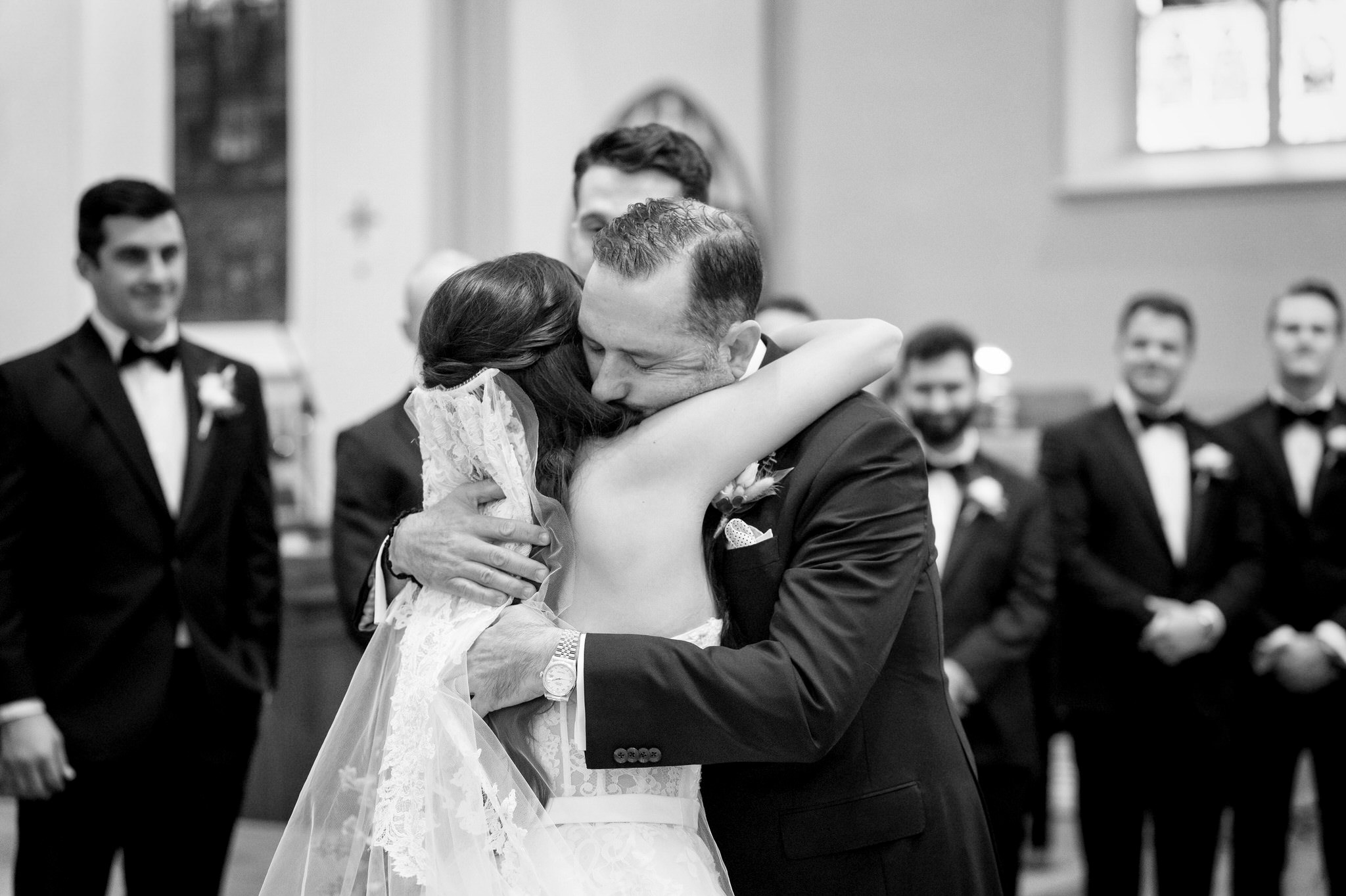 The father-of-the-bride hugs his daughter at the altar of St. Francis Xavier on her wedding day in downtown Petoskey.  