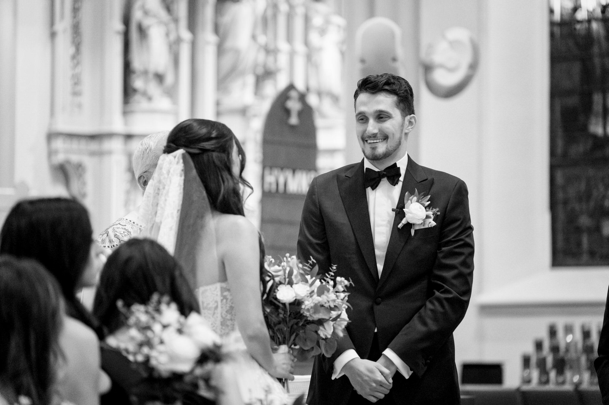 A bride and groom look at each other and smile on their wedding day at St. Francis Xavier church in Petoskey, MI. 