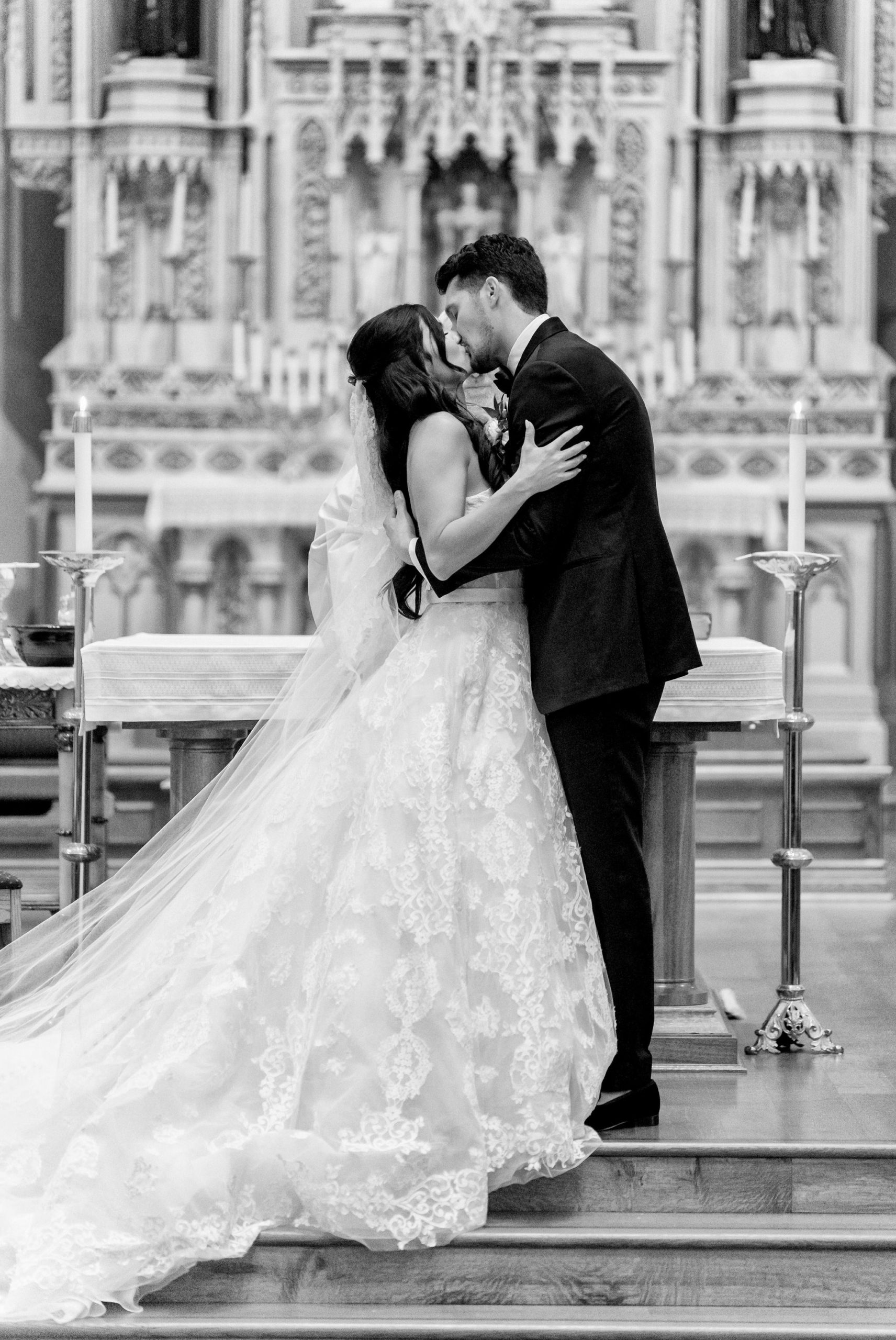 A couple kisses at the altar on their wedding day at St. Francis Xavier Church in Petoskey, MI.   