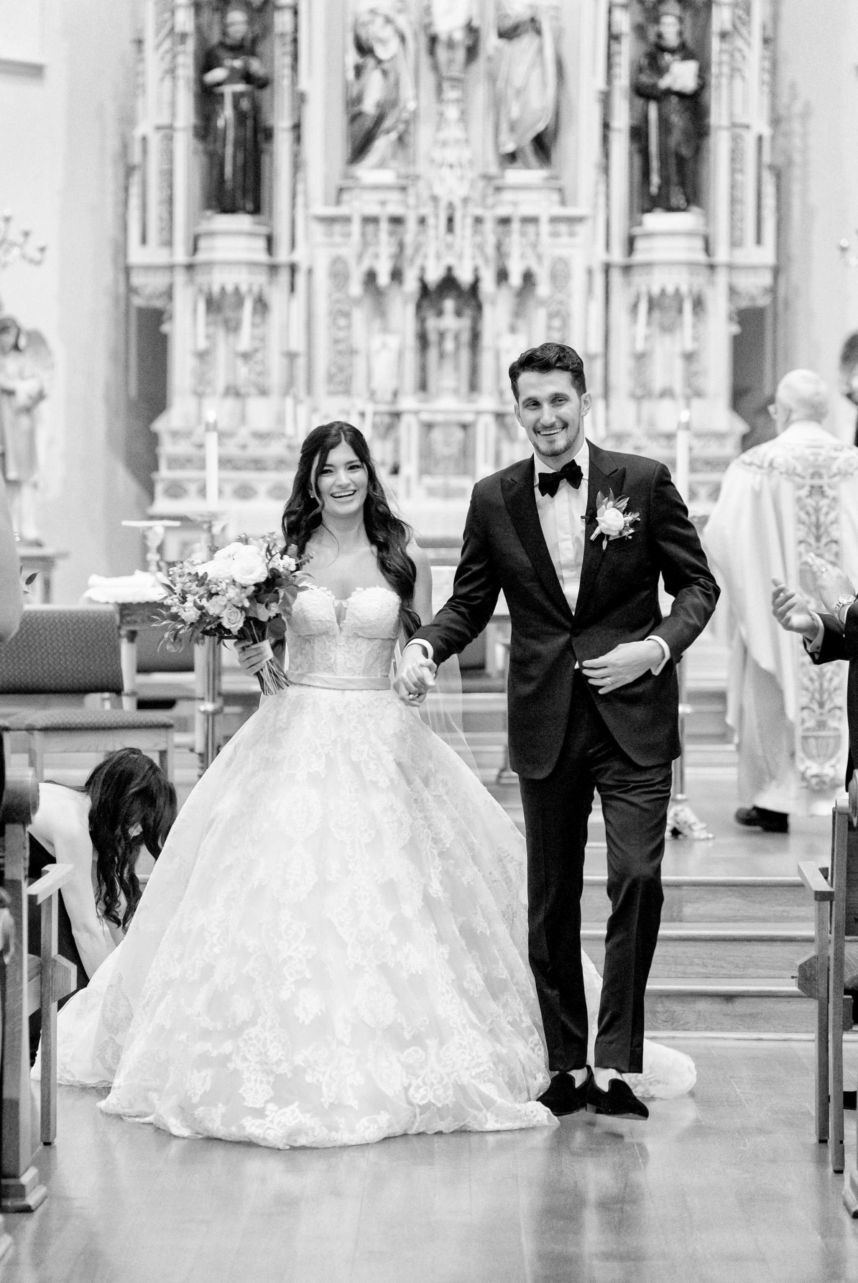 A couple smile as they walk down the aisle at St. Francis Xavier Church in Petoskey, MI.   