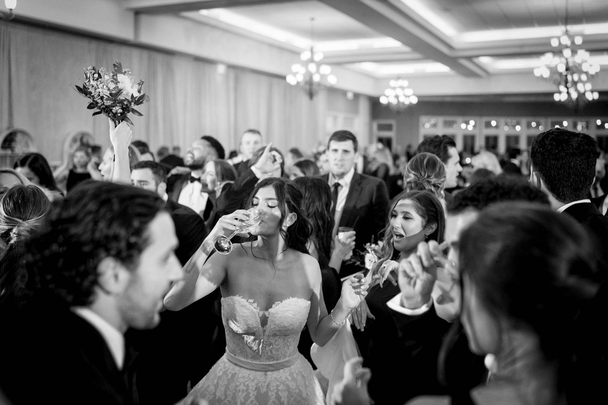 A bride takes a drink while surrounded by guests on her dance floor at Bay Harbor.  