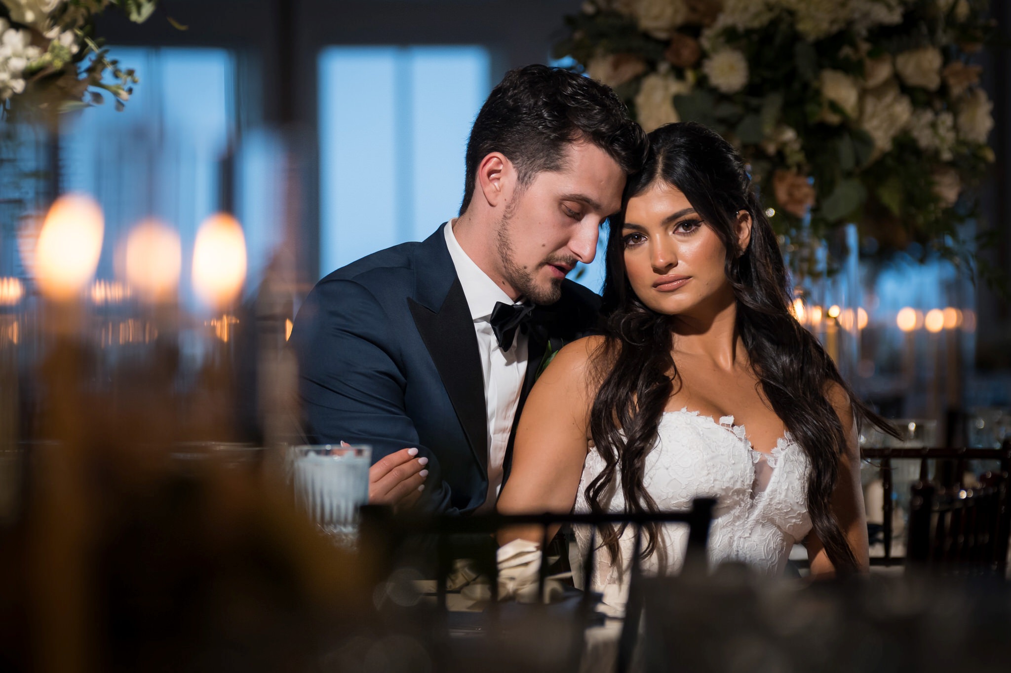 A bride and groom pose at their head table at their wedding at Bay Harbor.