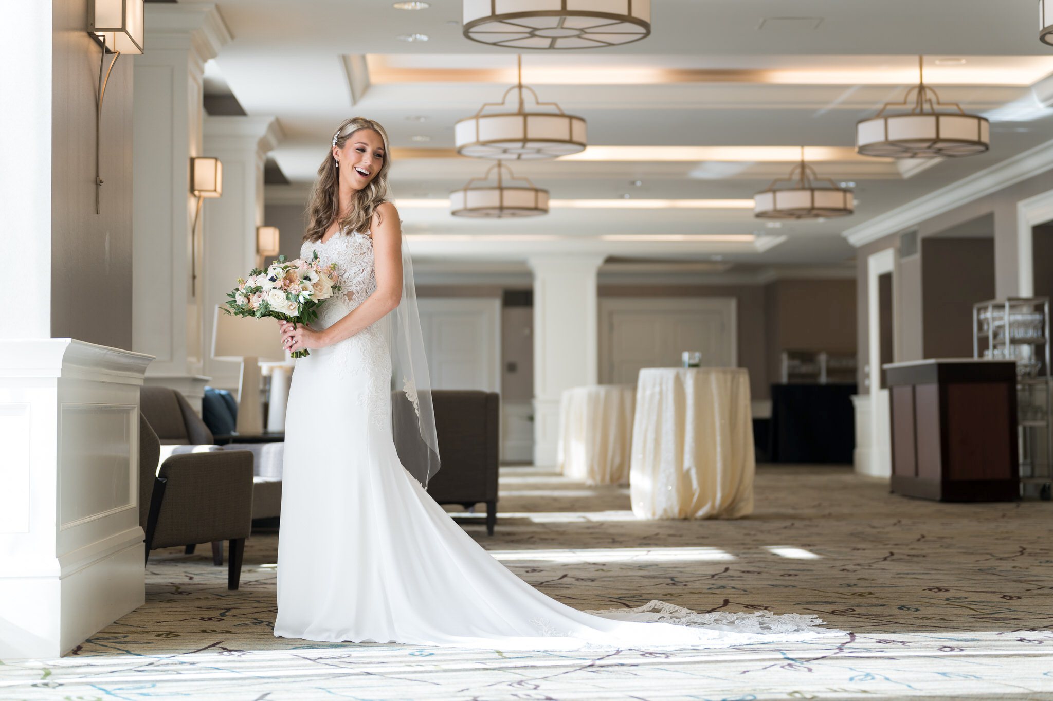 A bride, holding her bouquet and laughing while looking over her shoulder, gets ready for her Westin  Book Cadillac wedding.  