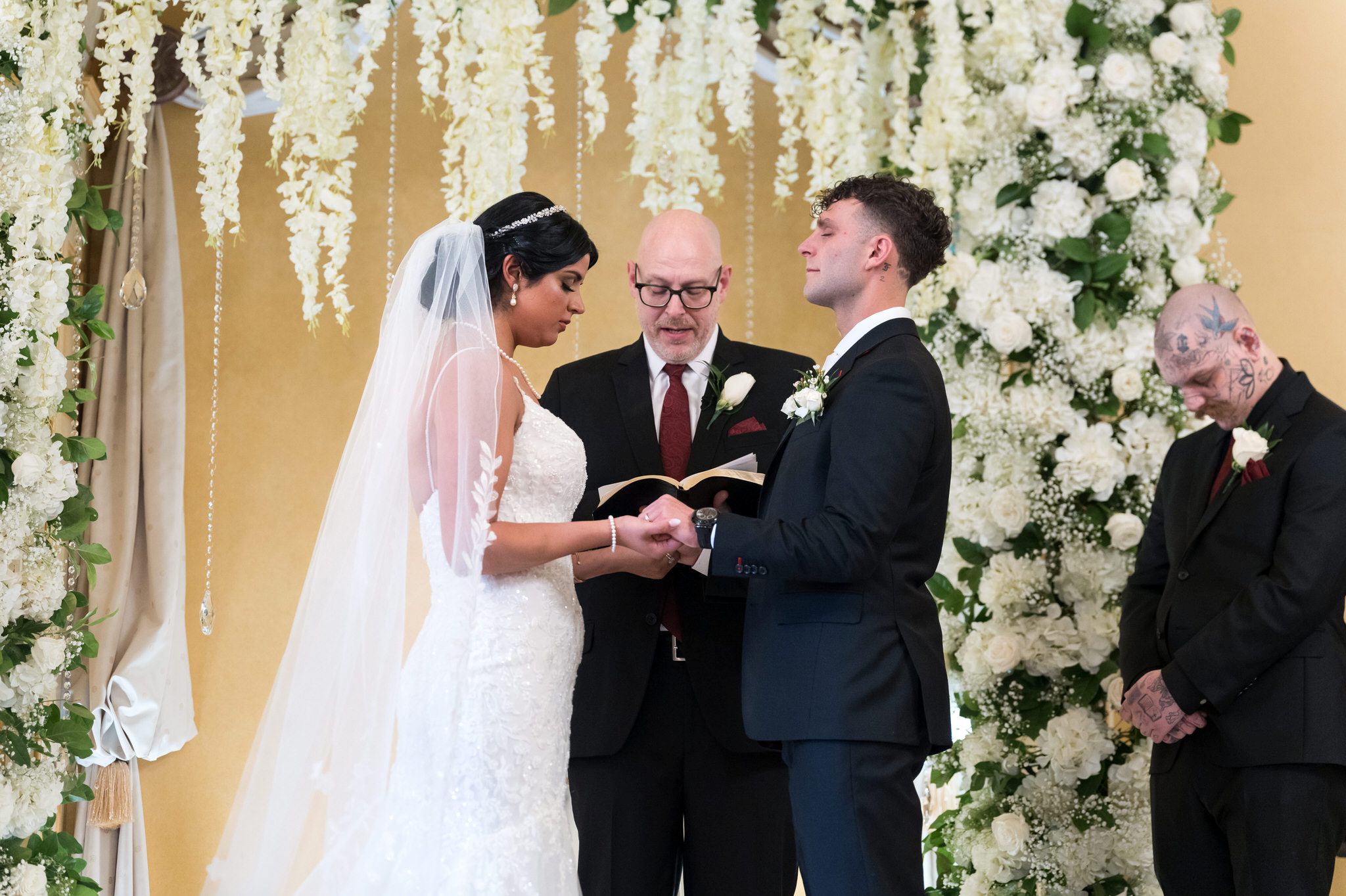 A bride and groom hold hands and pray at their Colony Club Detroit wedding ceremony. 