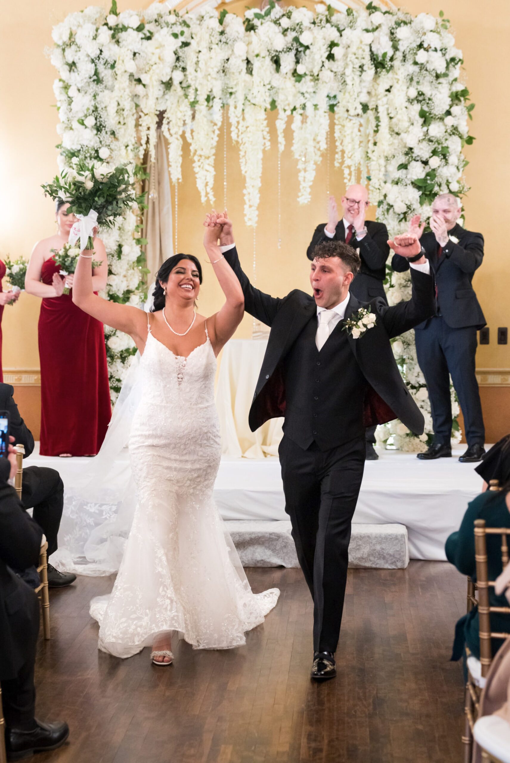 A bride and groom celebrate as they walk down the aisle at their Colony Club Detroit wedding ceremony. 