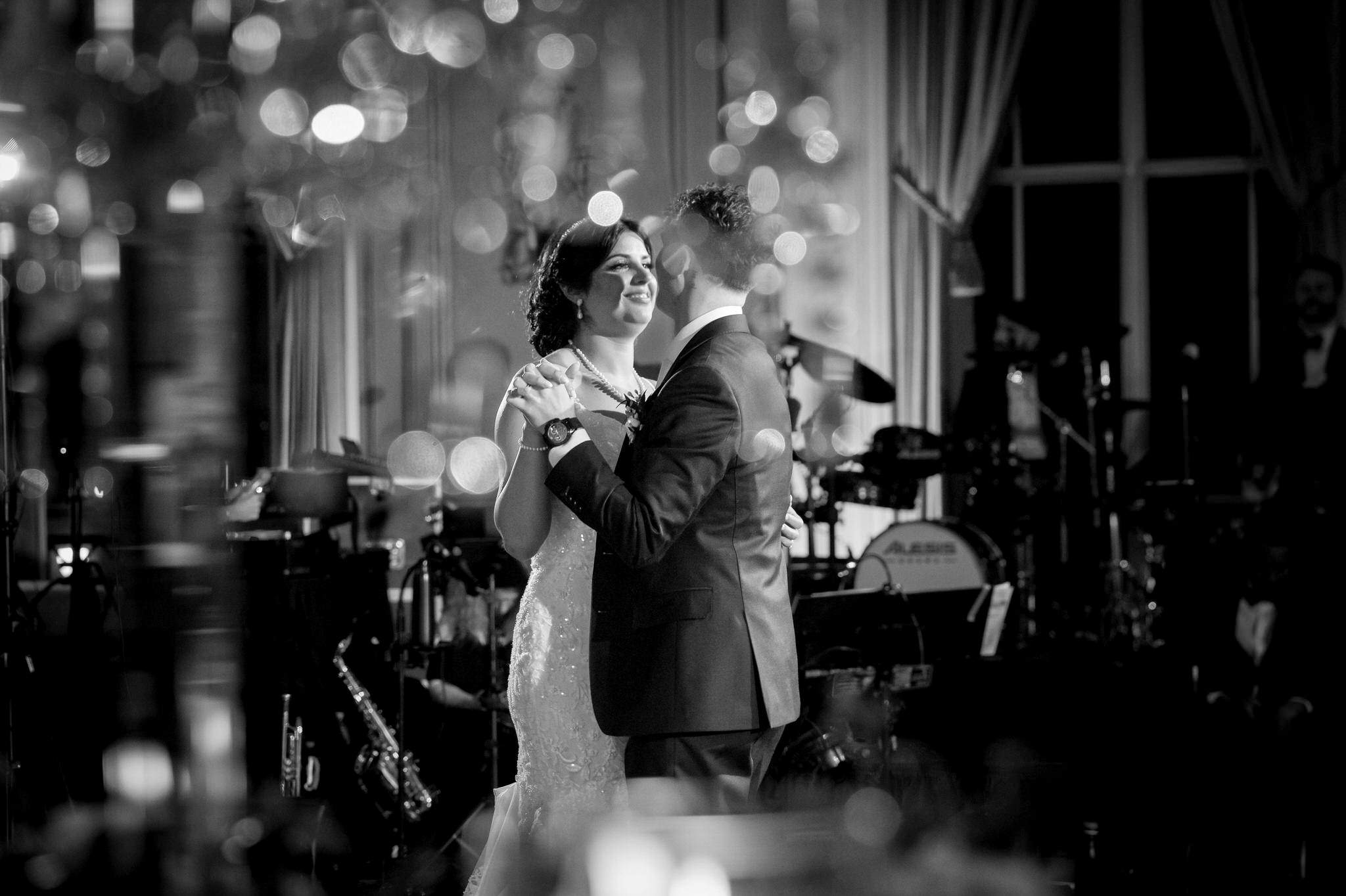 Shot through a centerpiece, a bride and groom share a first dance at their Colony Club Detroit wedding.