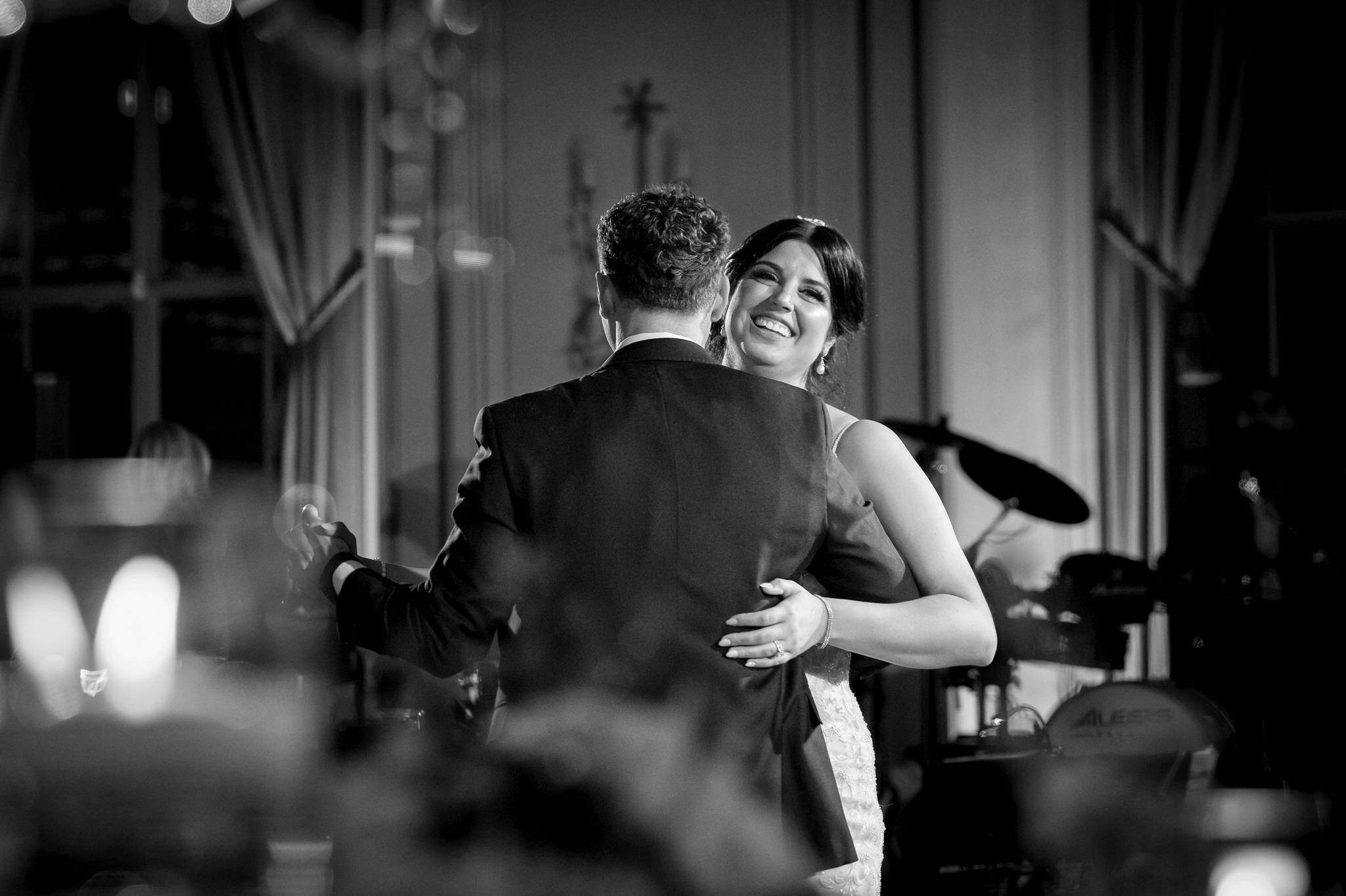 Shot through a centerpiece, a bride and groom share a first dance at their Colony Club Detroit wedding.