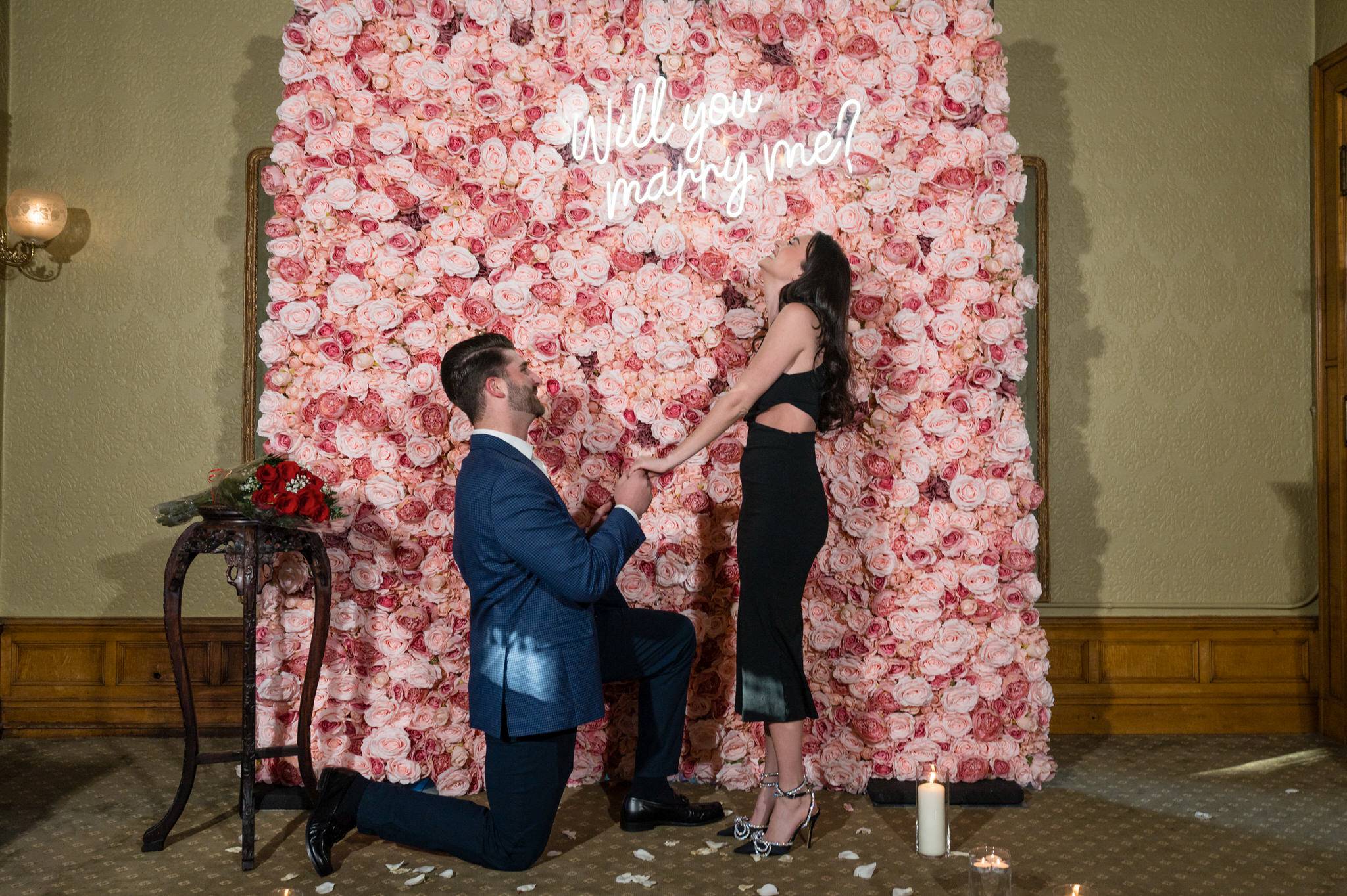 Marriage proposal at the Whitney Detroit in front of a pink rose flower wall
