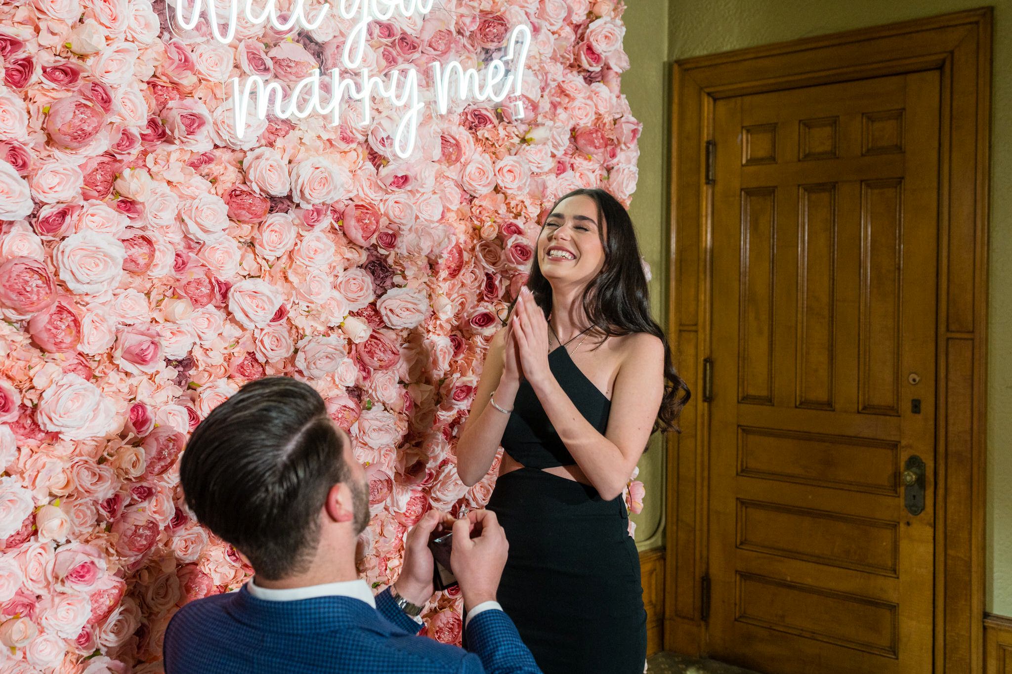 Proposal at the Whitney Detroit in front of a pink rose flower wall