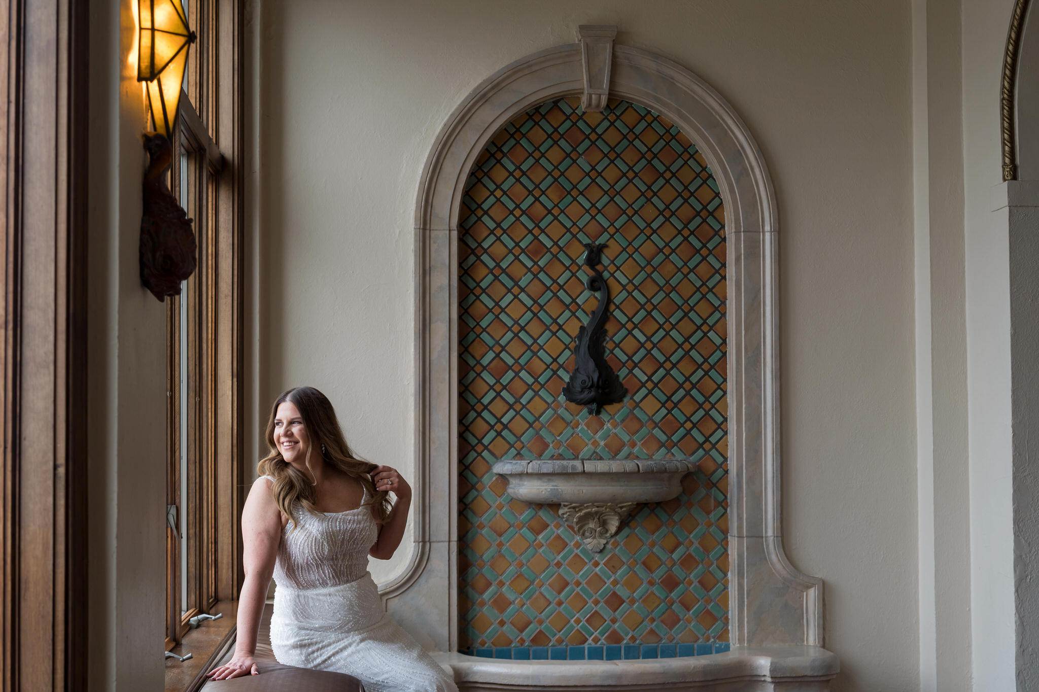 A bride sits and looks out the window at her Detroit Yacht Club wedding.