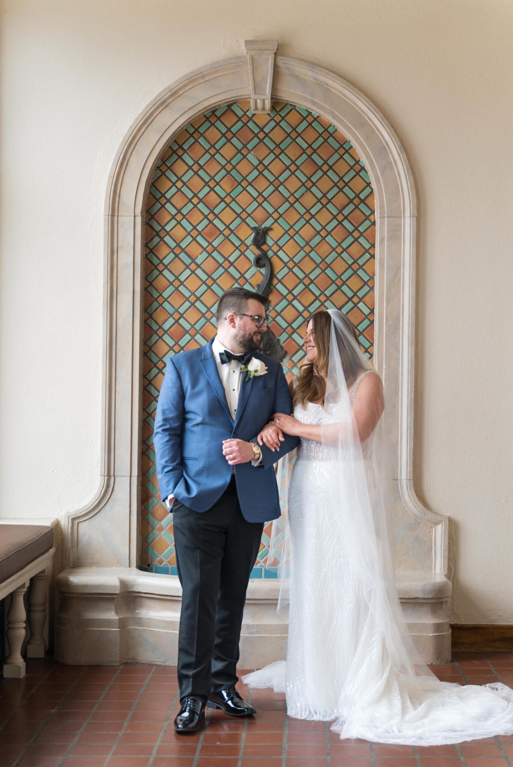 A bride and groom pose in front of an indoor fountain on their Detroit Yacht Club wedding. 