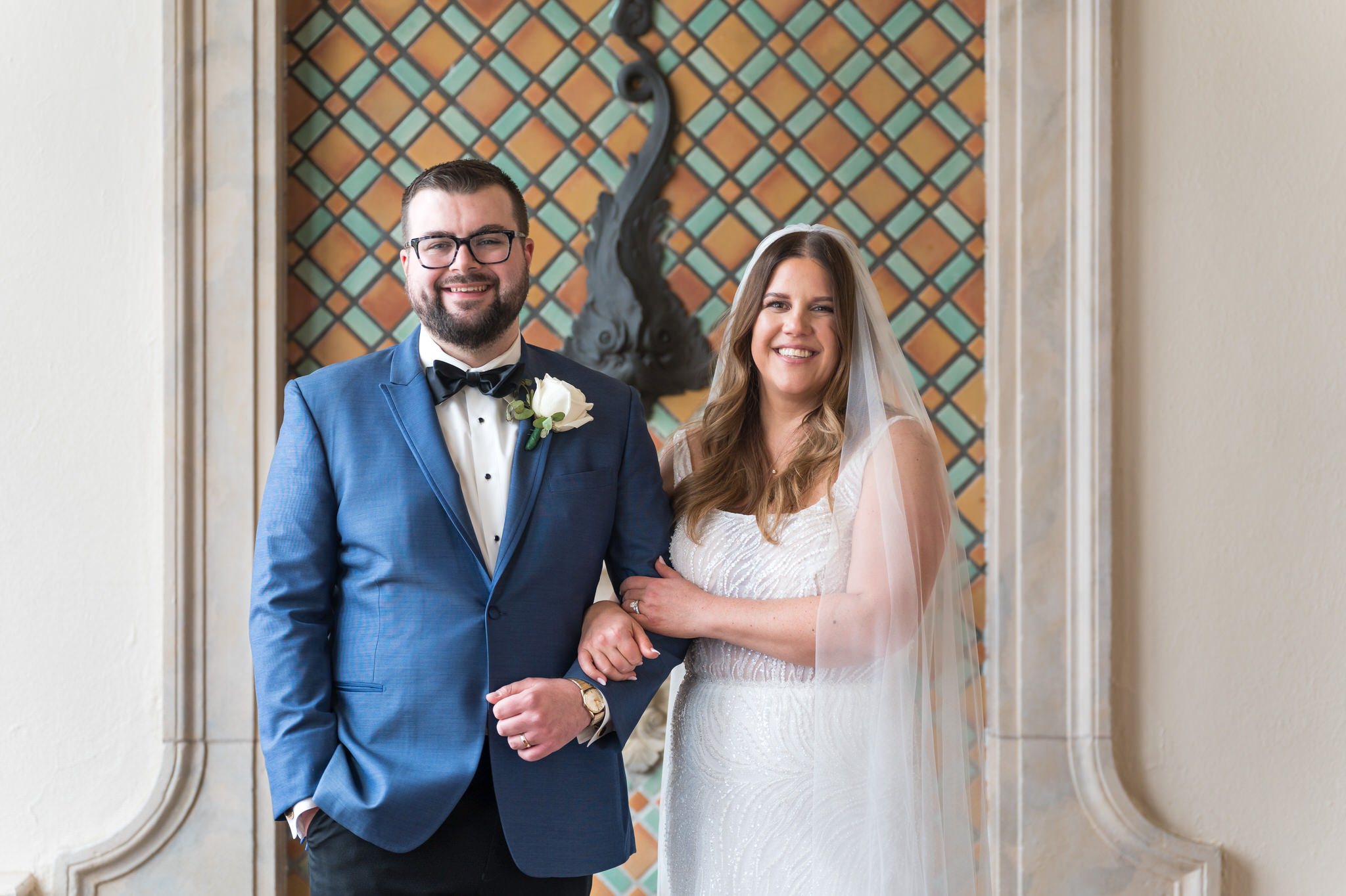 A bride and groom pose in front of an indoor fountain on their Detroit Yacht Club wedding. 