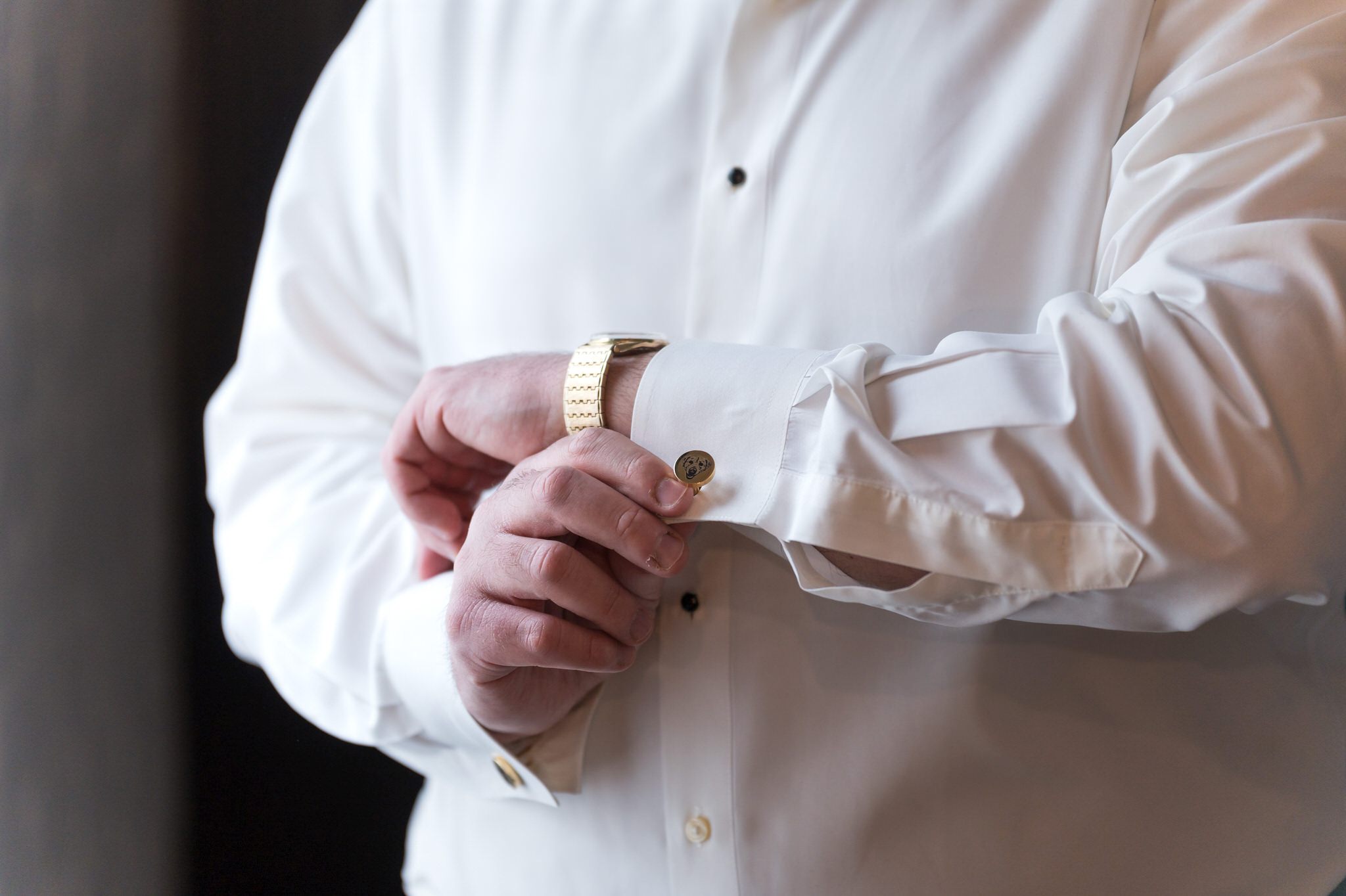 A groom fixes his custom dog cufflinks at the Foundation Hotel. 