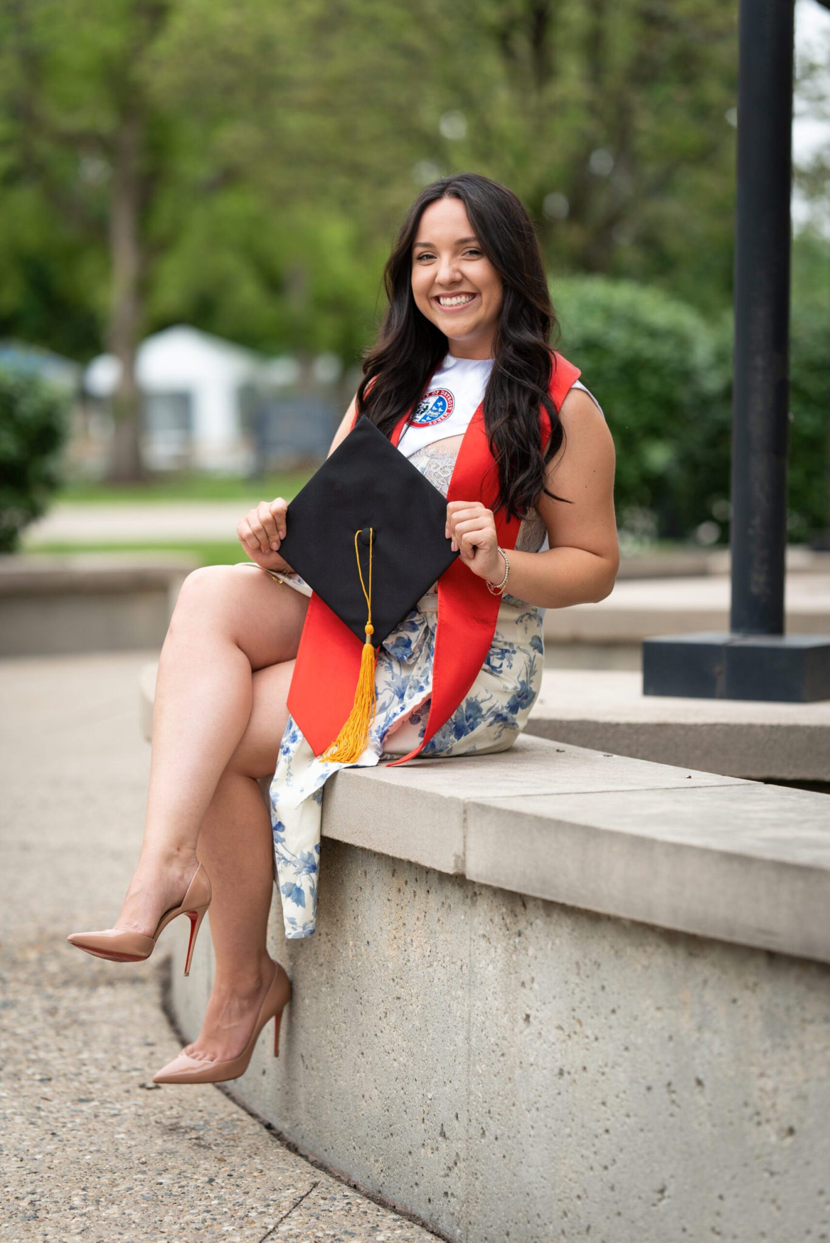 A girl poses holding a graduation cap for her college graduation photos.