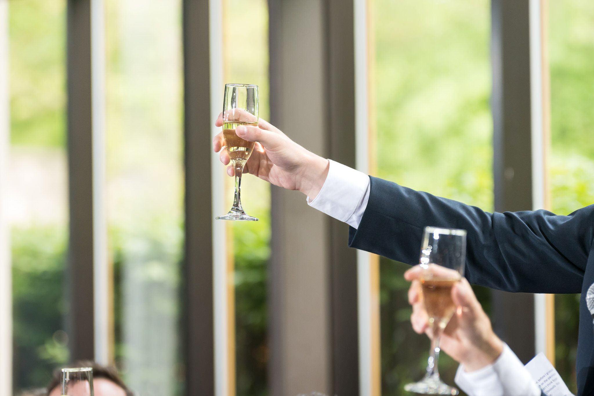 A champagne glass is raised during speeches at a wedding.  