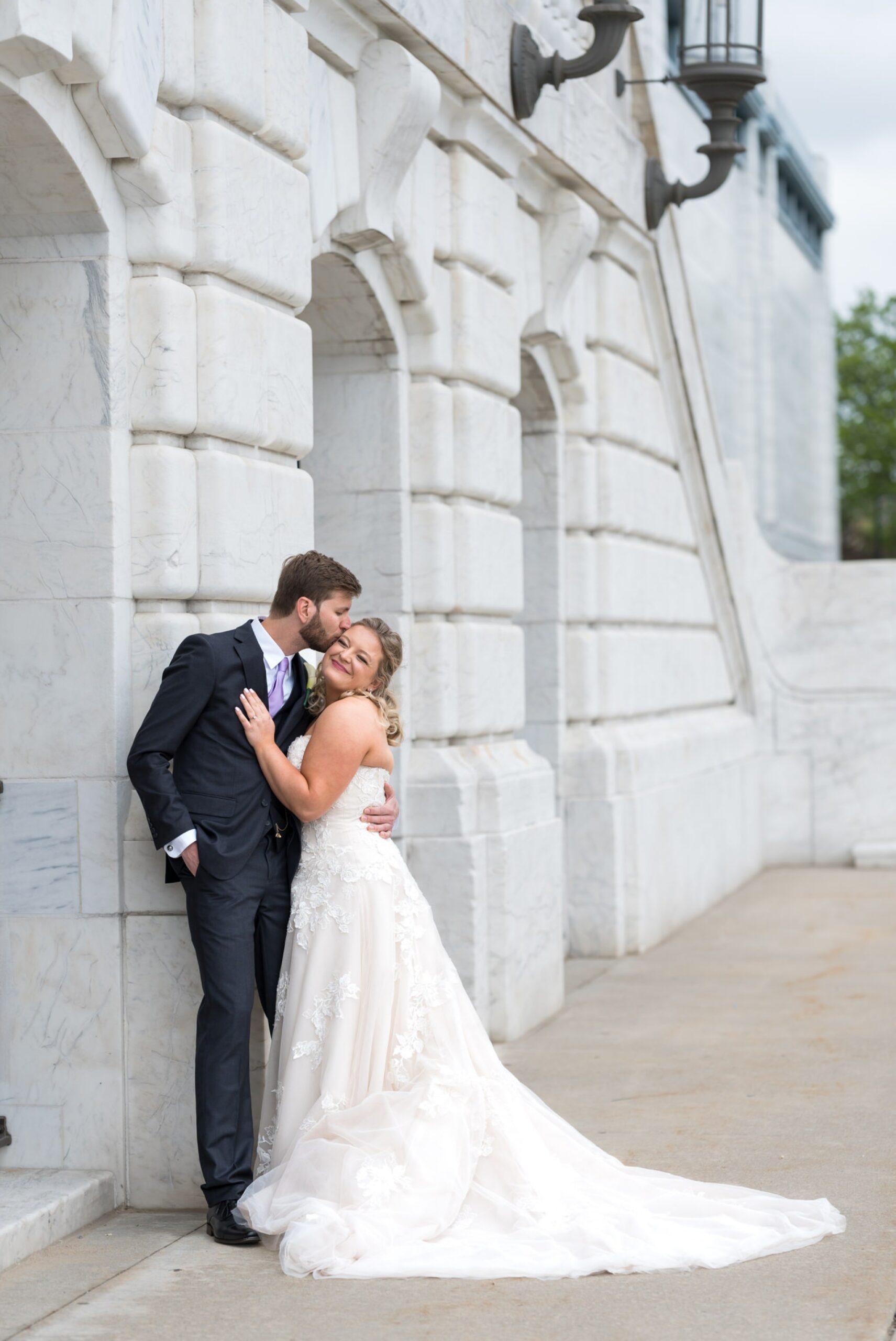 A bride and groom embrace outside of the Detroit Institute of Art on their wedding day.  